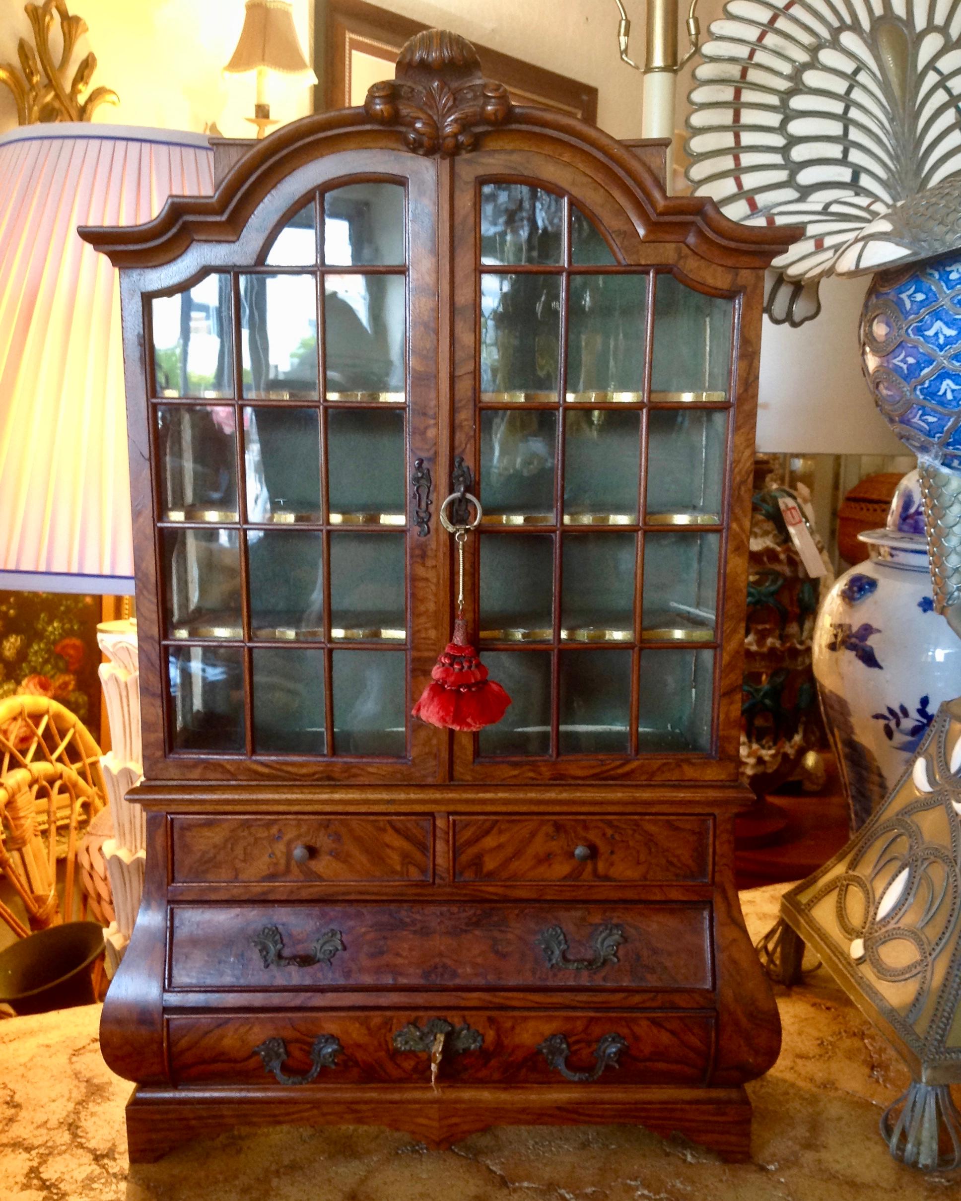 A rare and important miniature. The piece is fashioned with a bombe' base
and a top designed with a fleur de lis carved crown. The glass panes are set individually.
The serpentine shelves have gilded edges. It is fitted with 4 lined drawers and