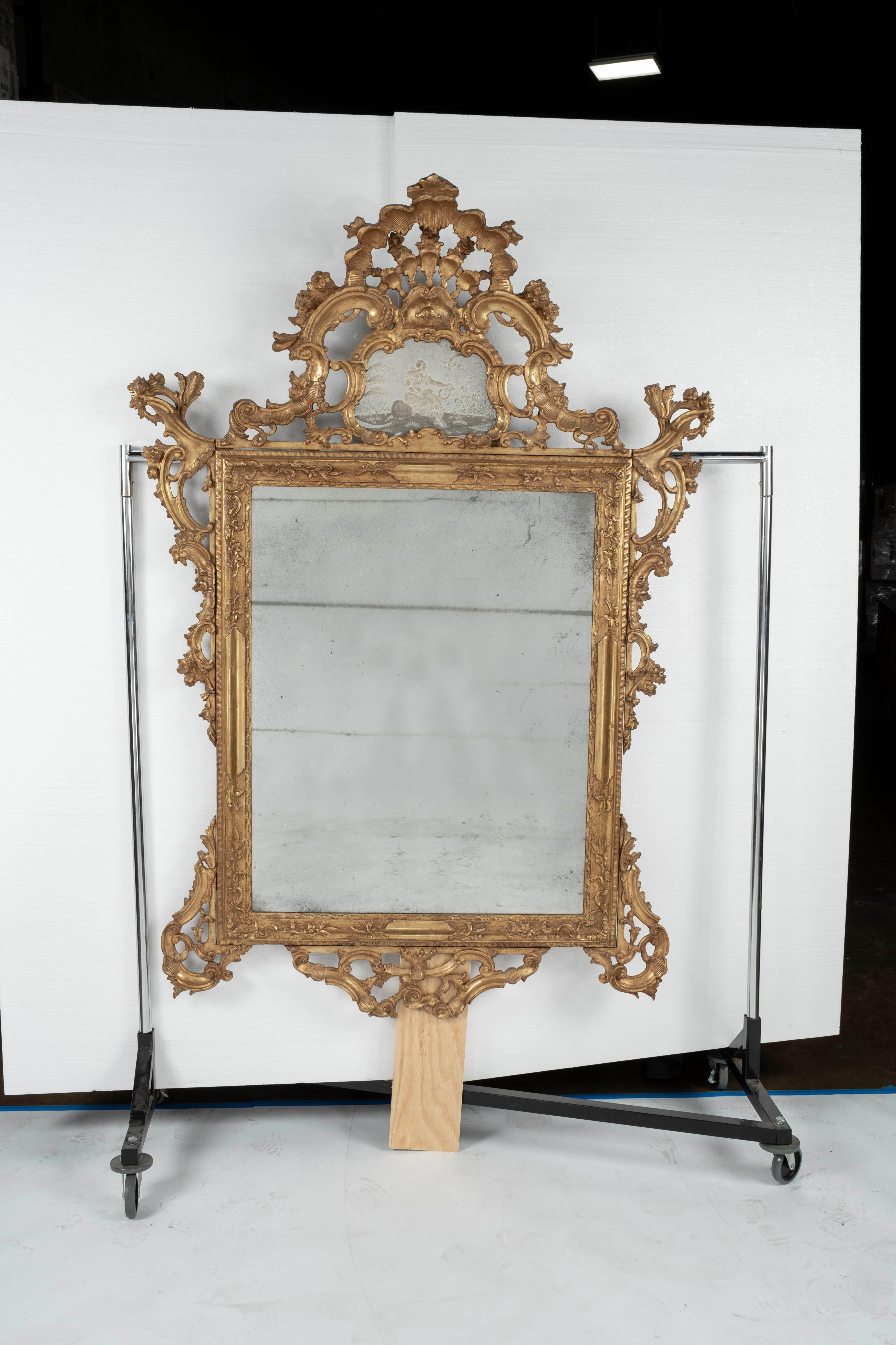 Louis XIV style carved and gilded mirror with etched glass inset
depicting a woman playing a lyre surrounded by a pierced shell-shaped
crest. Oxidized glass is age appropriate.