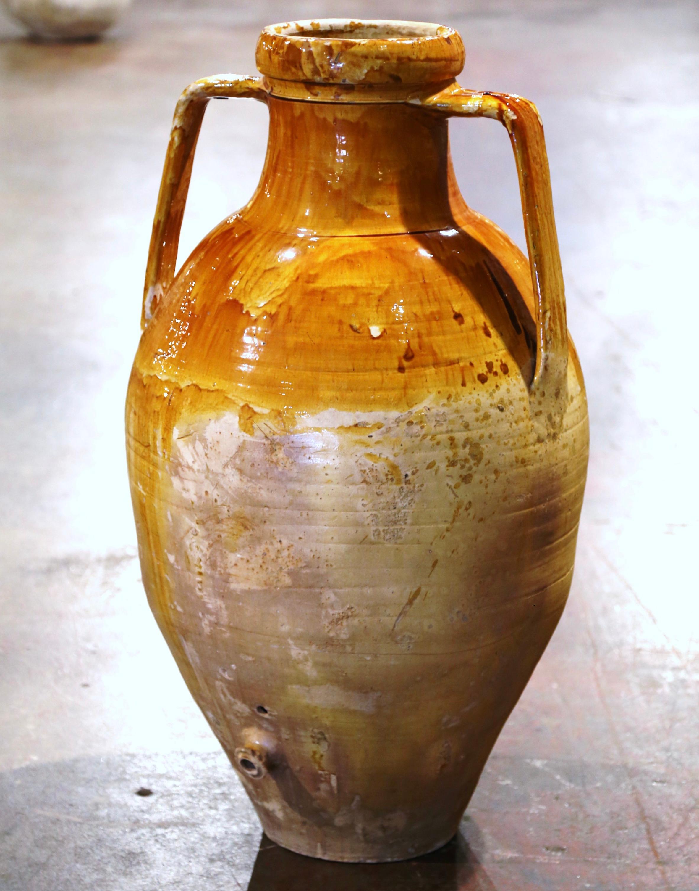 Add a Mediterranean touch to your indoor or outdoor spaces with this elegant antique terracotta Amphora. Crafted in southern Italy circa 1860, the large urn has a traditional round shape over a long neck; it is dressed with double handles, and