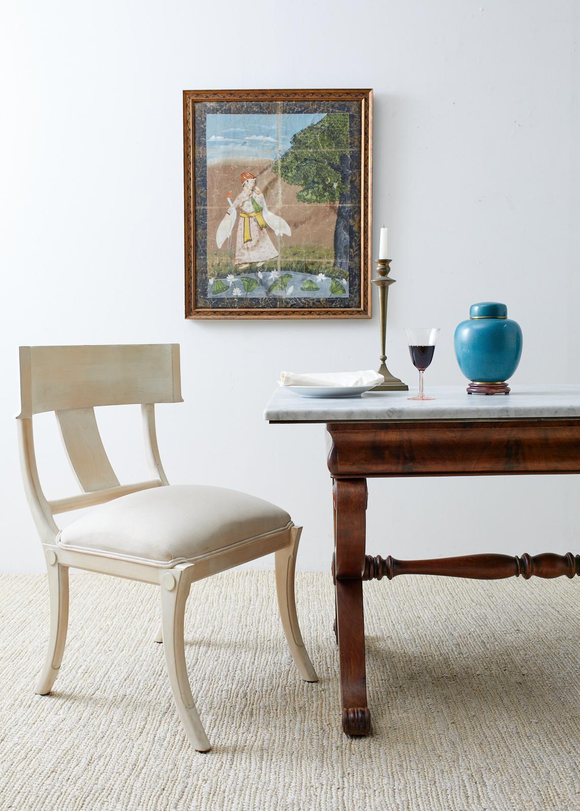 Distinctive early 19th century Italian library table featuring a mahogany X-form base supporting a white marble top. Beautifully crafted with radiant flame mahogany veneers decorating the apron. The curule neoclassical style legs have scrolled ends