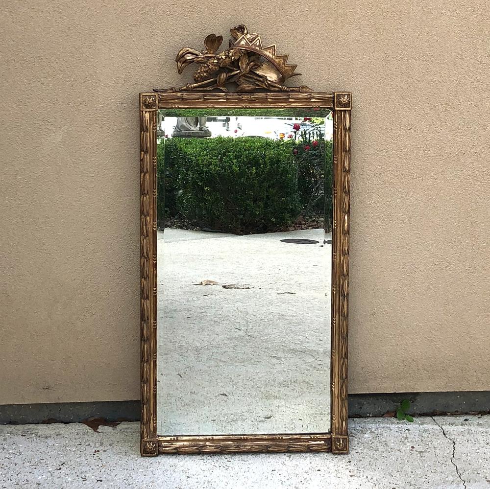 19th century Italian neoclassical hand carved giltwood mirror is an intriguing work with symbols of royalty atop the framework! Centered along the top is a juxtaposition of a golden crown, a floral wreath, scepters and foliate embellishments. The