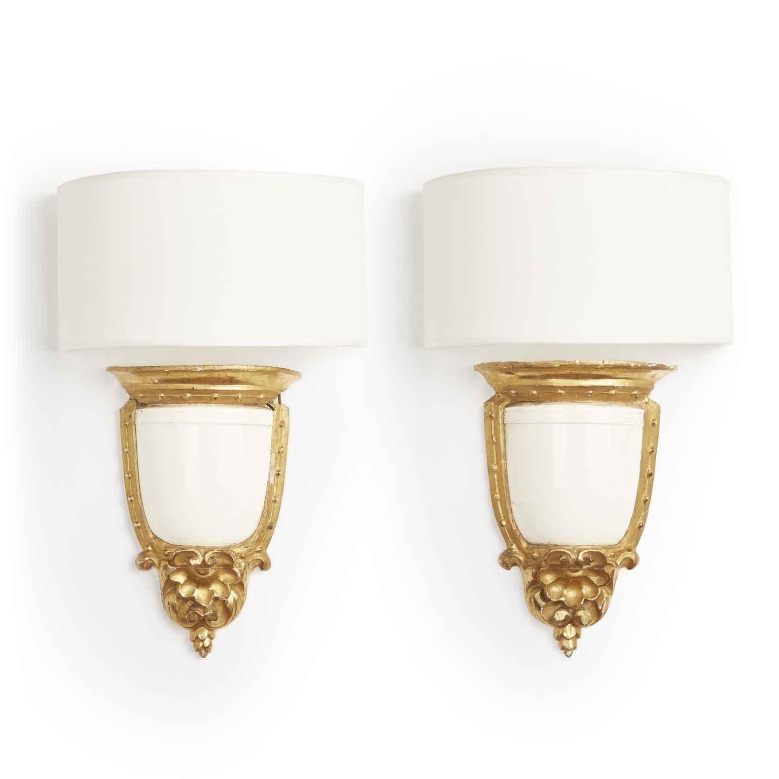 Early 19th century Neoclassical carved and gilded wall brackets realized with a white ivory color majolica demi vase of the Italian manufacture Giustiniani from Neaples. This unique and elegant pair od Italian artworks can be used as wall lights