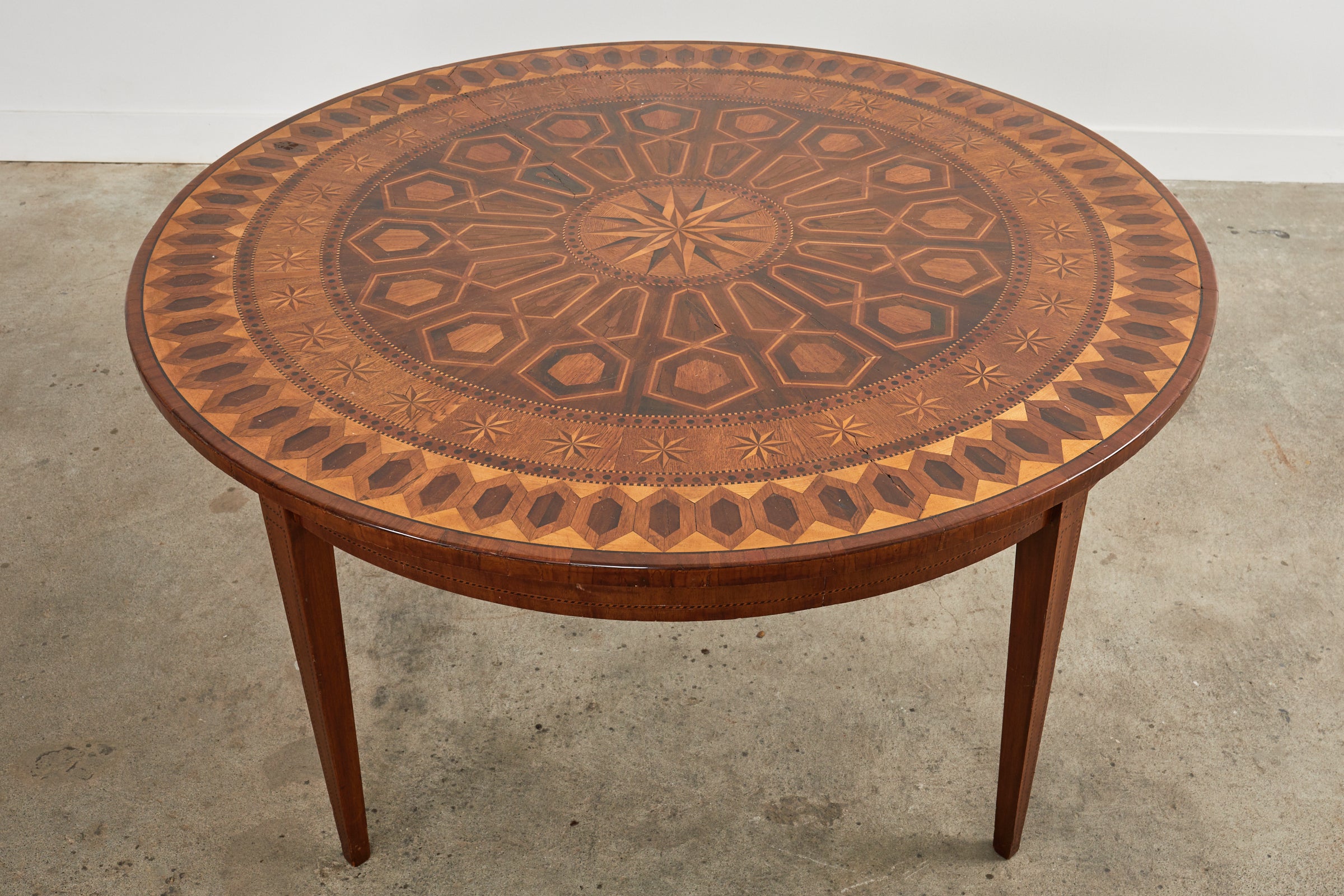 Fantastique table de centre ou table à manger italienne de la fin du 19e siècle, décorée dans le goût néoclassique. Fabriqué en noyer, le plateau rond présente des motifs complexes de marqueterie et de placage de parquet. Centré par une étoile