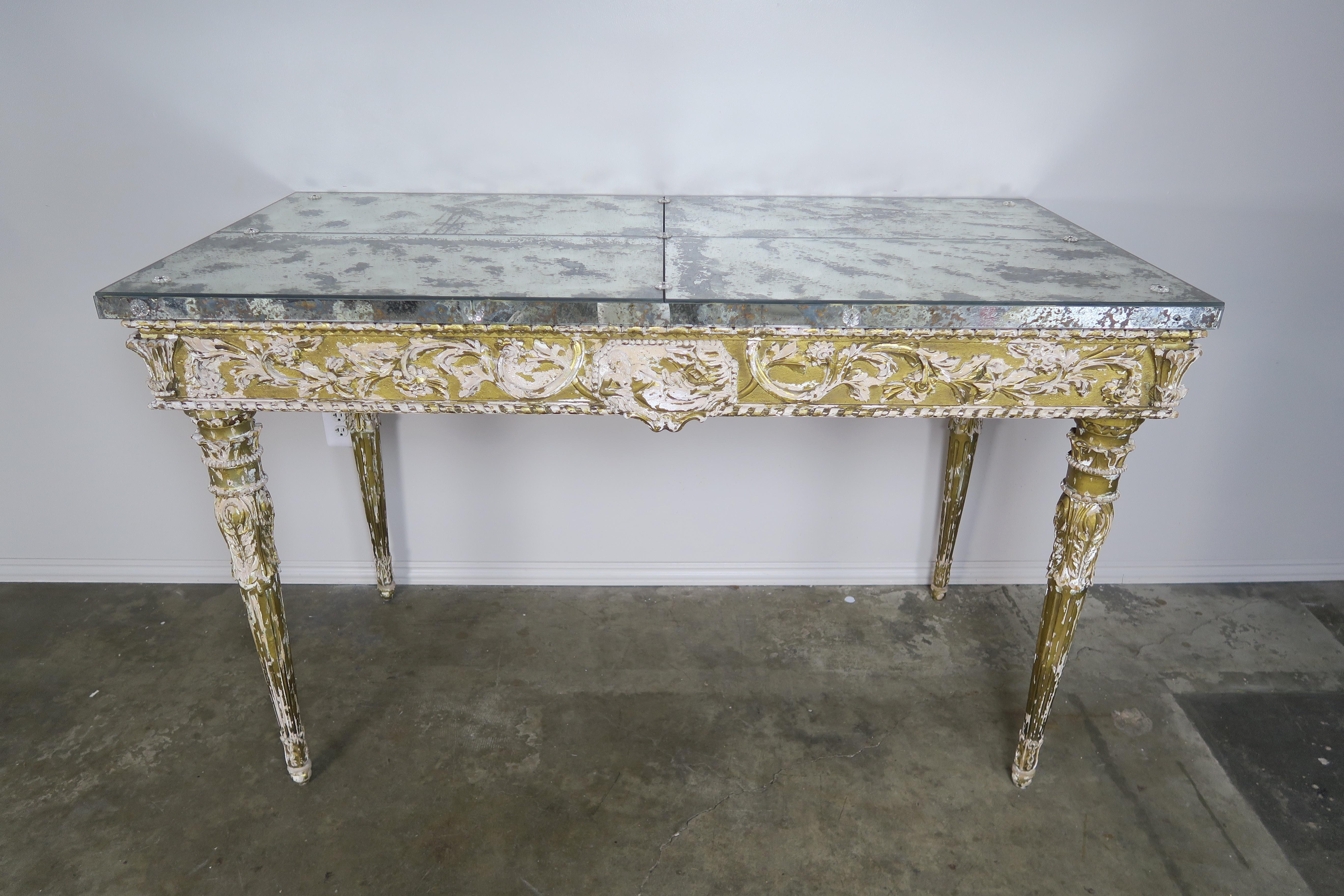 19th century Italian neoclassical style giltwood console standing on four straight tapered fluted legs. Beautiful intricate carving throughout including the figure of a reclining man and swirling acanthus leaves throughout. Worn 