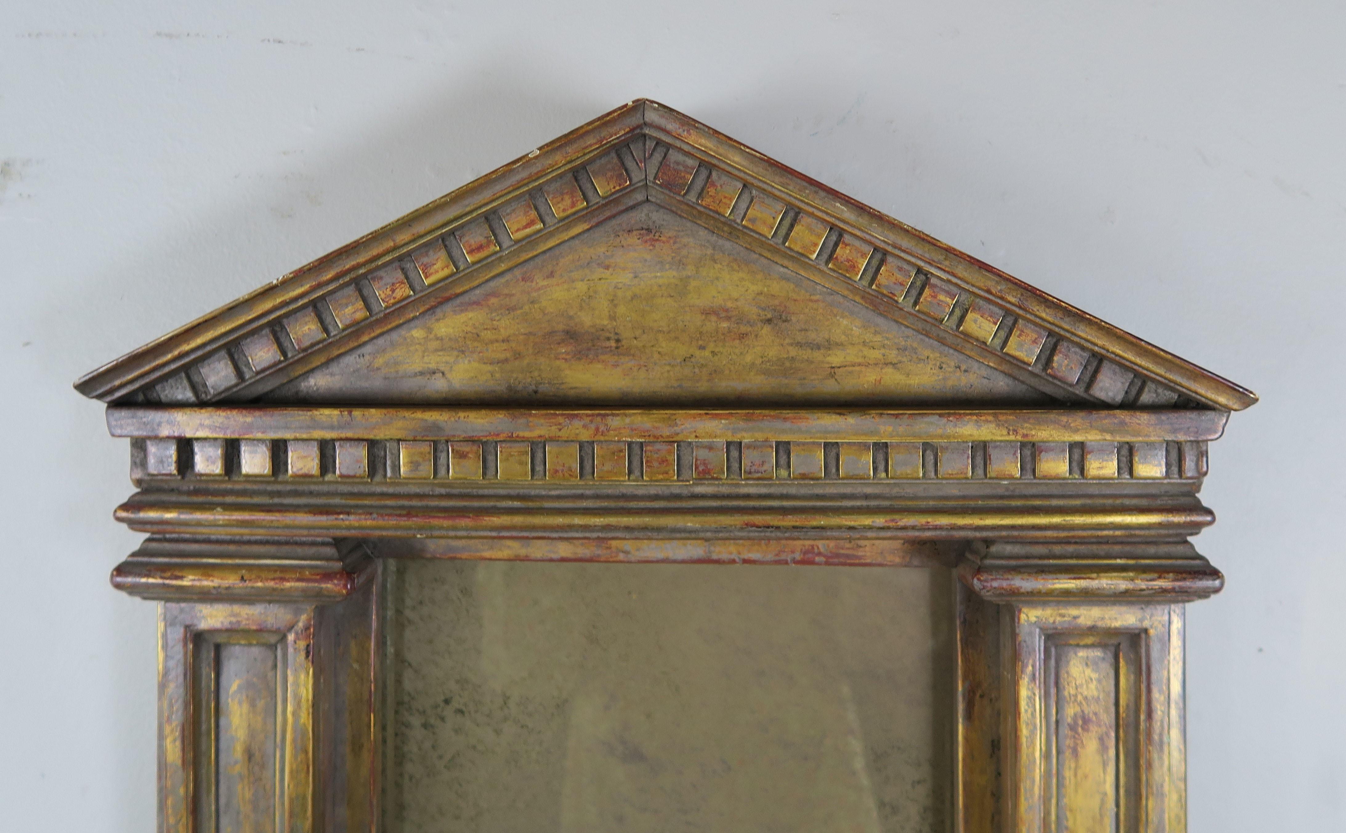 19th century Italian neoclassical style carved giltwood mirror in the shape of a portico. Aged smokey mirror from year of exposure. Distressed finish with missing gilt throughout.