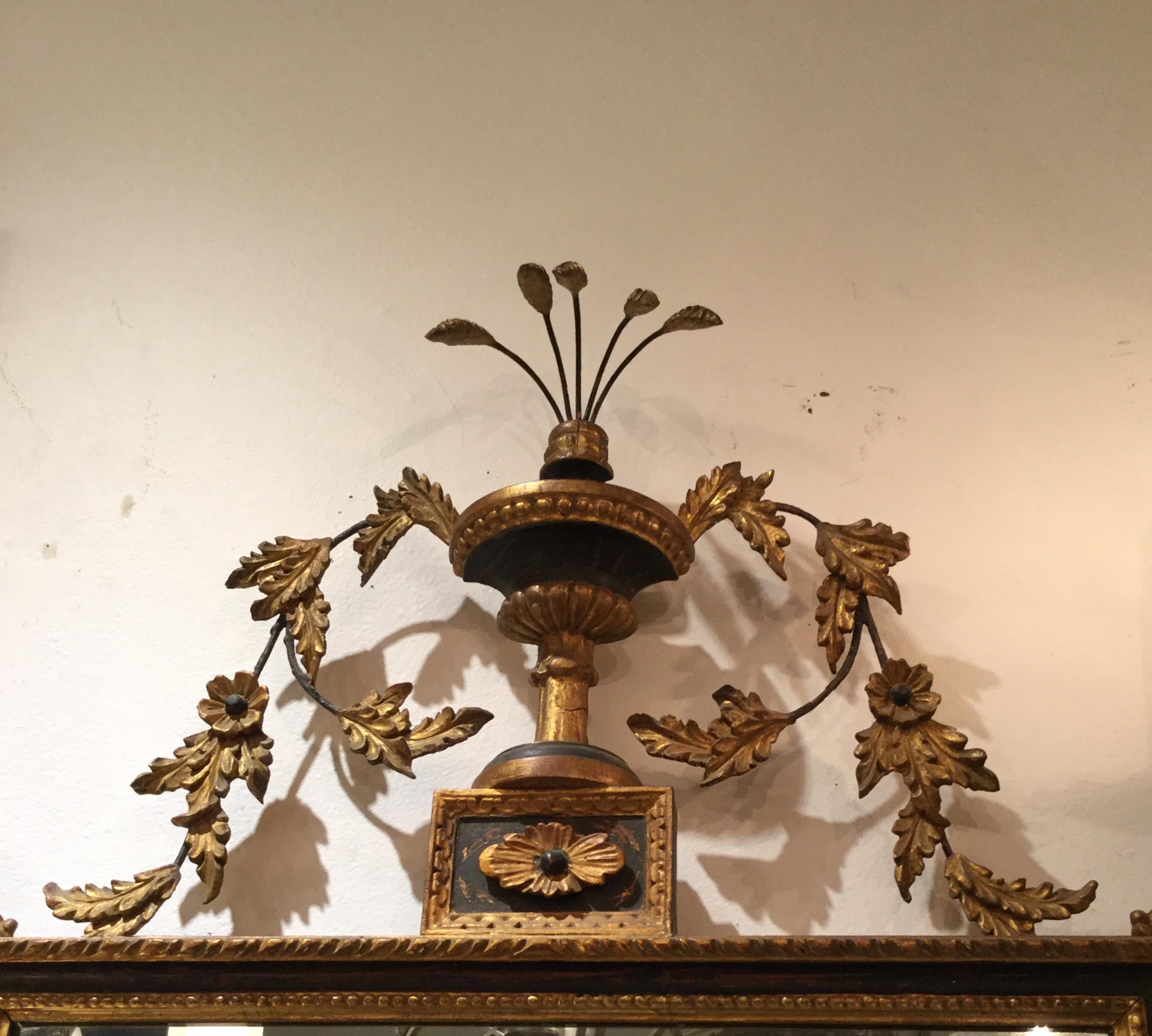 An elegant 19th century Italian neoclassical style carved wood mirror.
Nice gilded leaves and flowers that have been attached to metal adorn the mirror all the way around with larger carvings top and bottom and a crown of wheat at the top. The