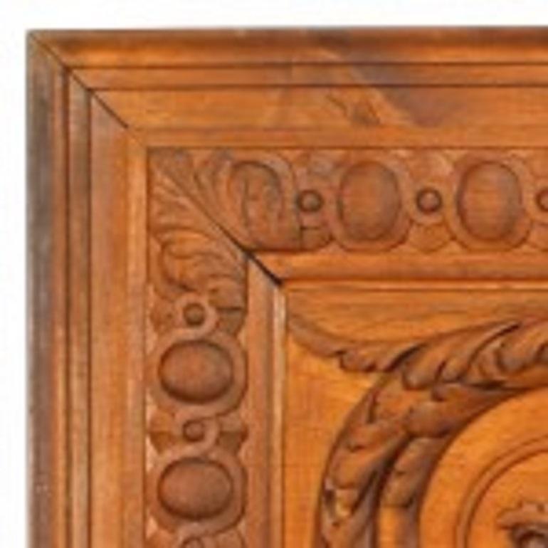 Panel de nogal tallado de estilo neoclásico italiano del siglo XIX con tallas en relieve de
delfines y frutas con un diseño de volutas y una corona central.