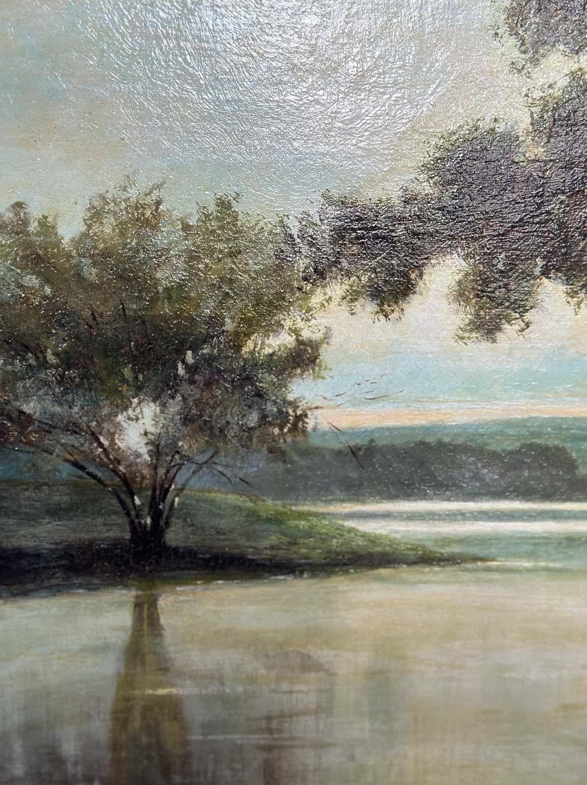 Sereine huile sur toile représentant une vue d'un lac et un pêcheur dans son bateau ainsi que des arbres tout autour. Les tons bleus et verts ajoutent à l'ambiance paisible du paysage. L'œuvre est protégée par un cadre en bois doré sculpté à la