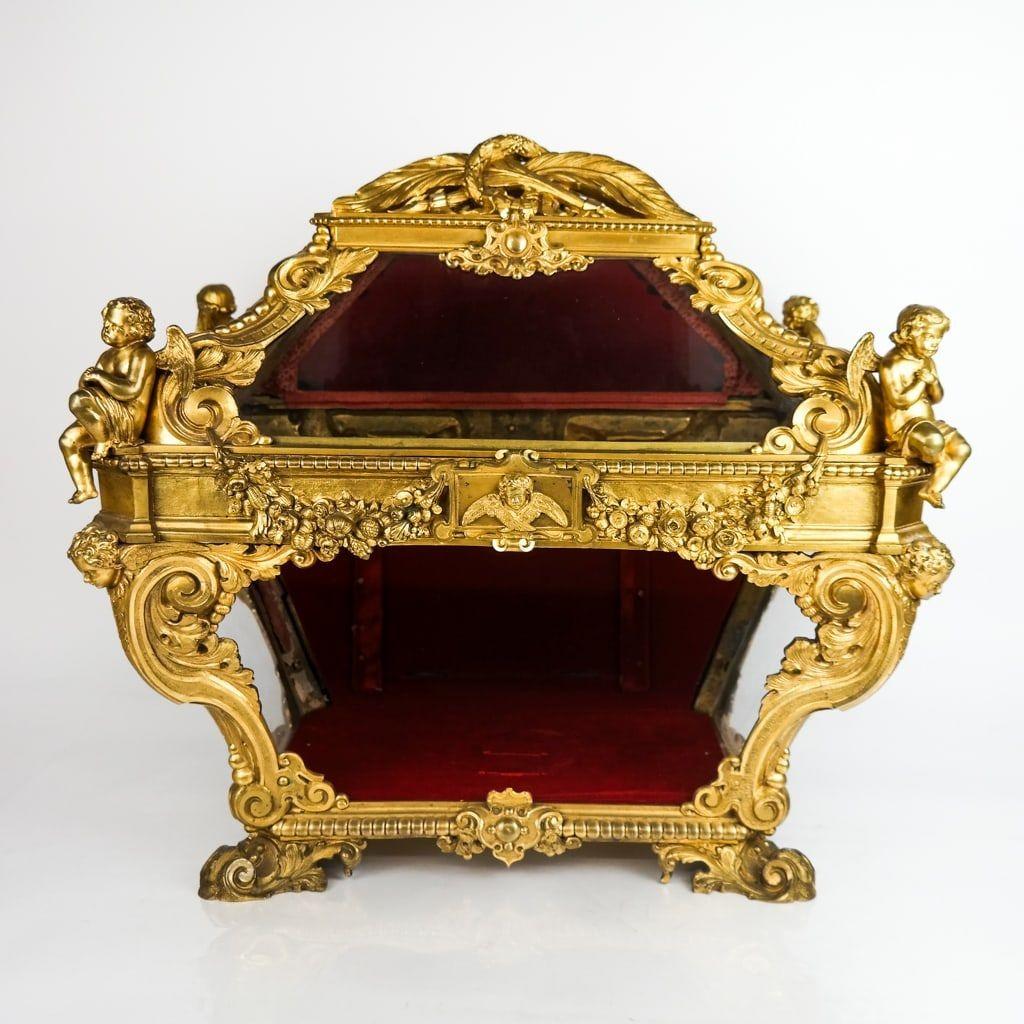 Our magnificent Italian gilt bronze reliquary casket from the Baroque Revival period, decorated with garlands and foliate scrolls and putti at the corners, with glazed panels and fitted with later red velvet lining.  21 inches tall, 22 1/4 in wide