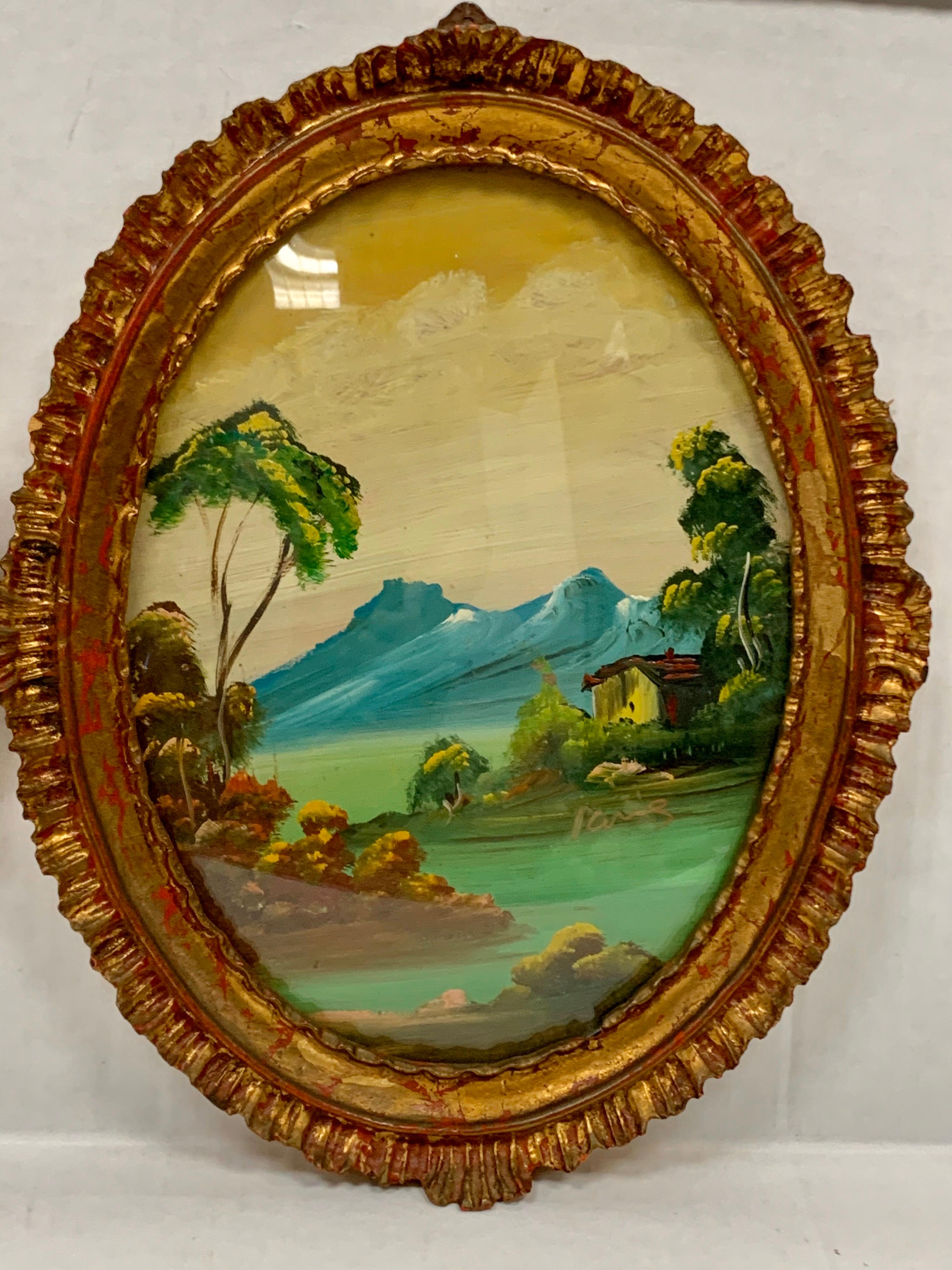 A pair of 19th century oval Italian hand painted landscape sceneries framed inside delicate gold giltwood frames and protected under convex glass. Signed illegibly.