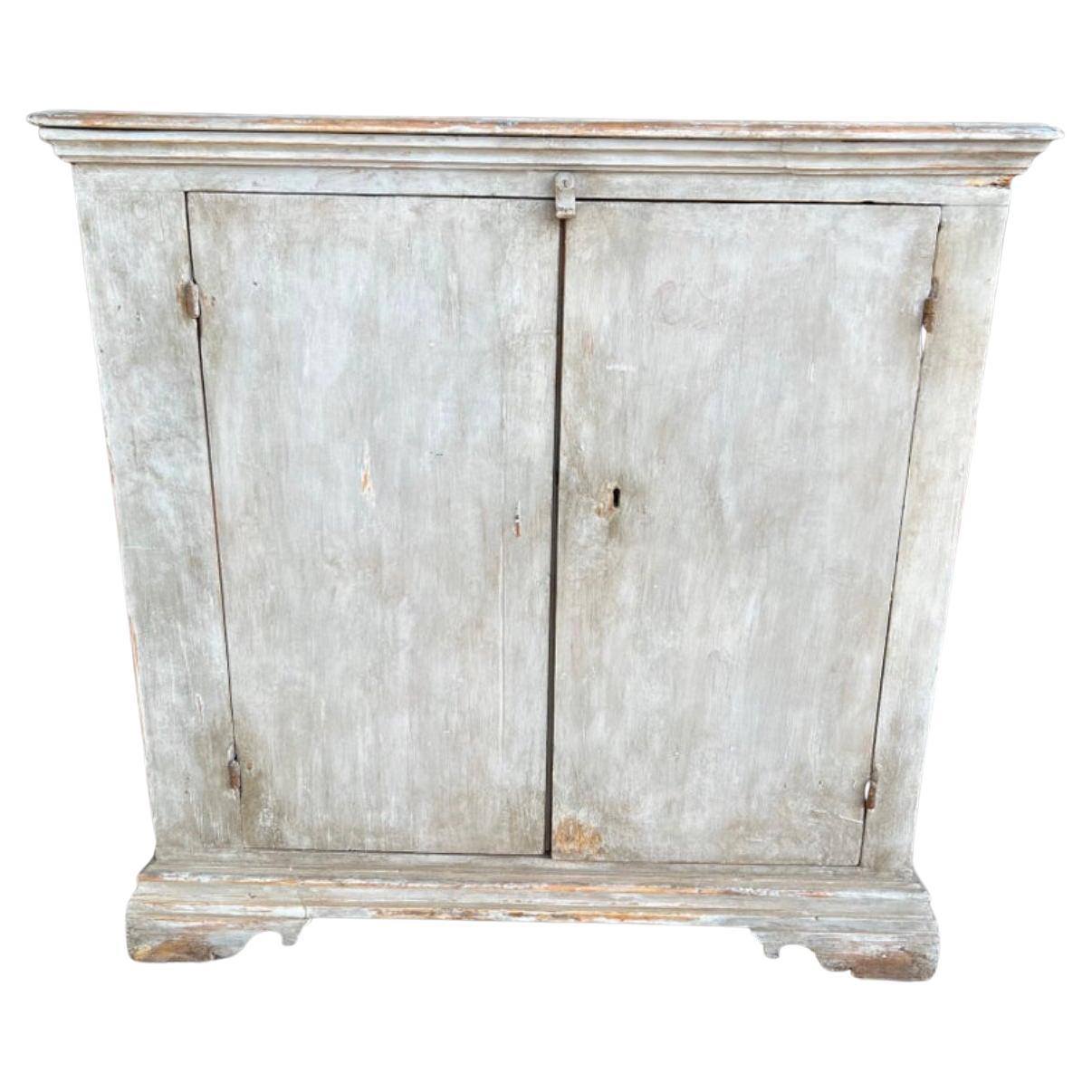 A beautiful blue toned painted Italian cabinet that features two doors. This piece is perfect for any design space, use in an entry way with a mirror or painting above it and decorative objects atop, use in a laundry room to store odds and ends, use
