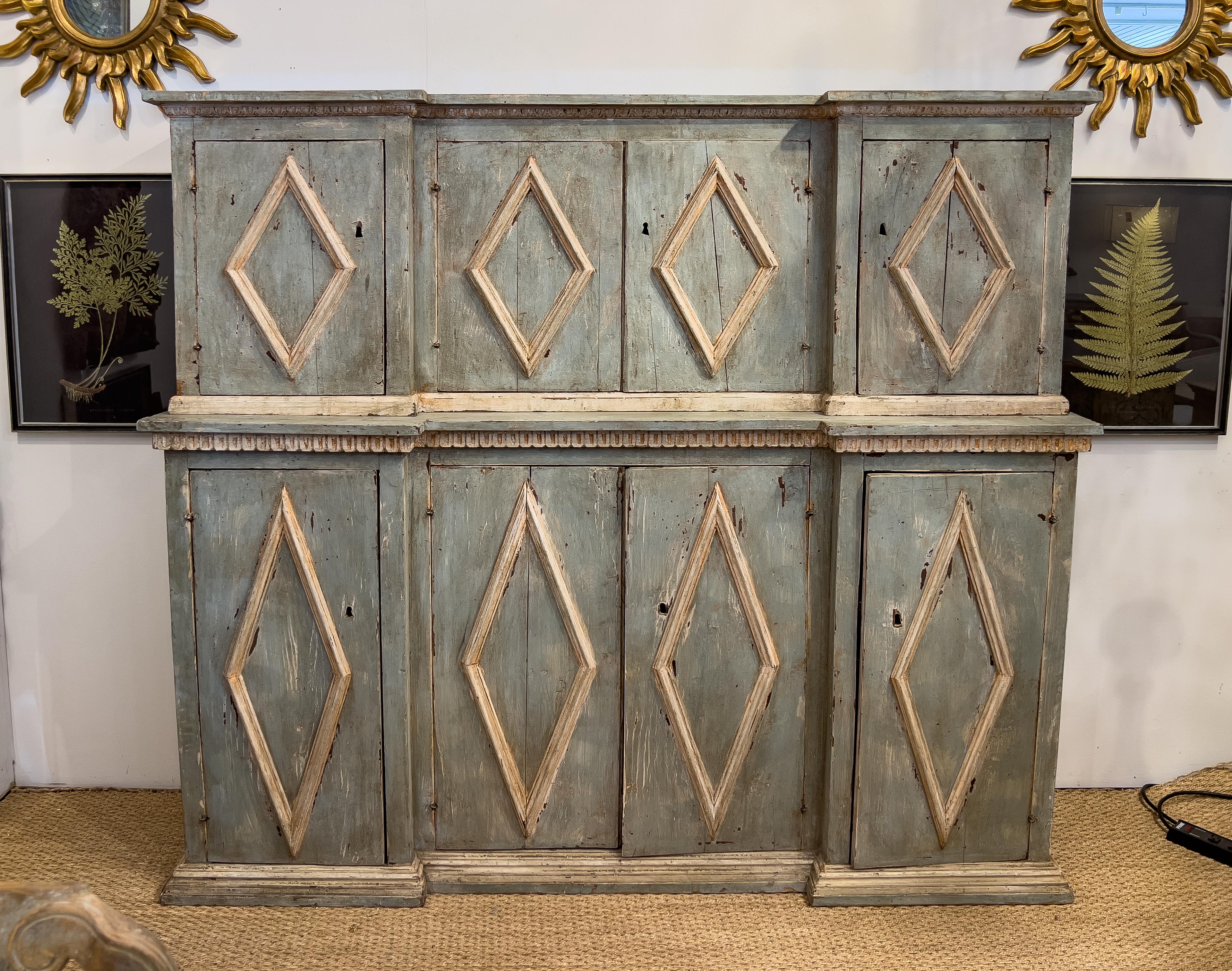 19th Century Italian Painted Cabinet with an inverted break front design. This piece has 8 doors that have a diamond shape raised molding, a plinth base and stylized dental molding.