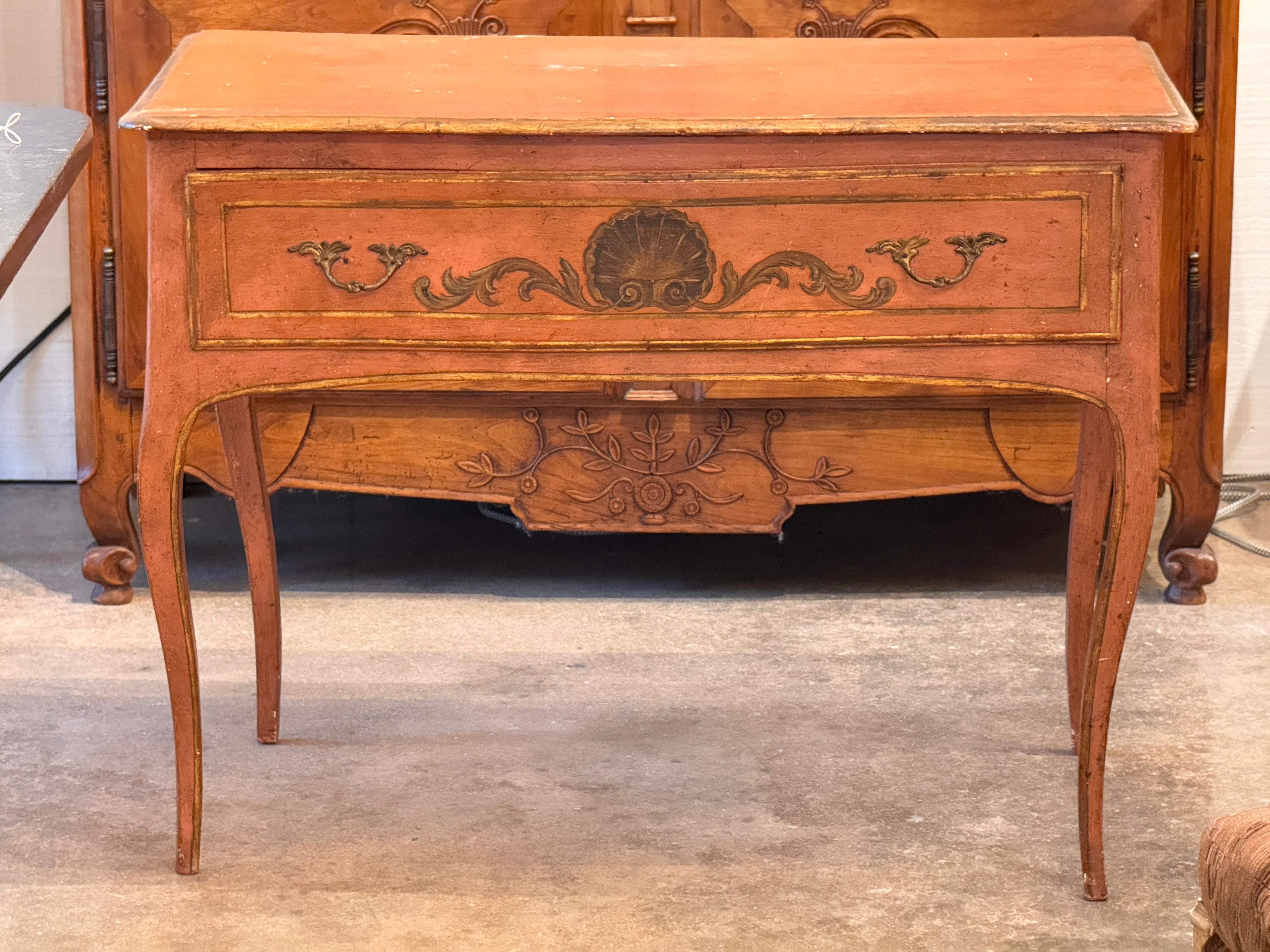 19th century Italian console table with a shaped apron and cabriole legs, finished in original painted terracotta tones with gilded details. The drawer front features a central shell motif flanked by scrolling decoration. Interior of the drawer is