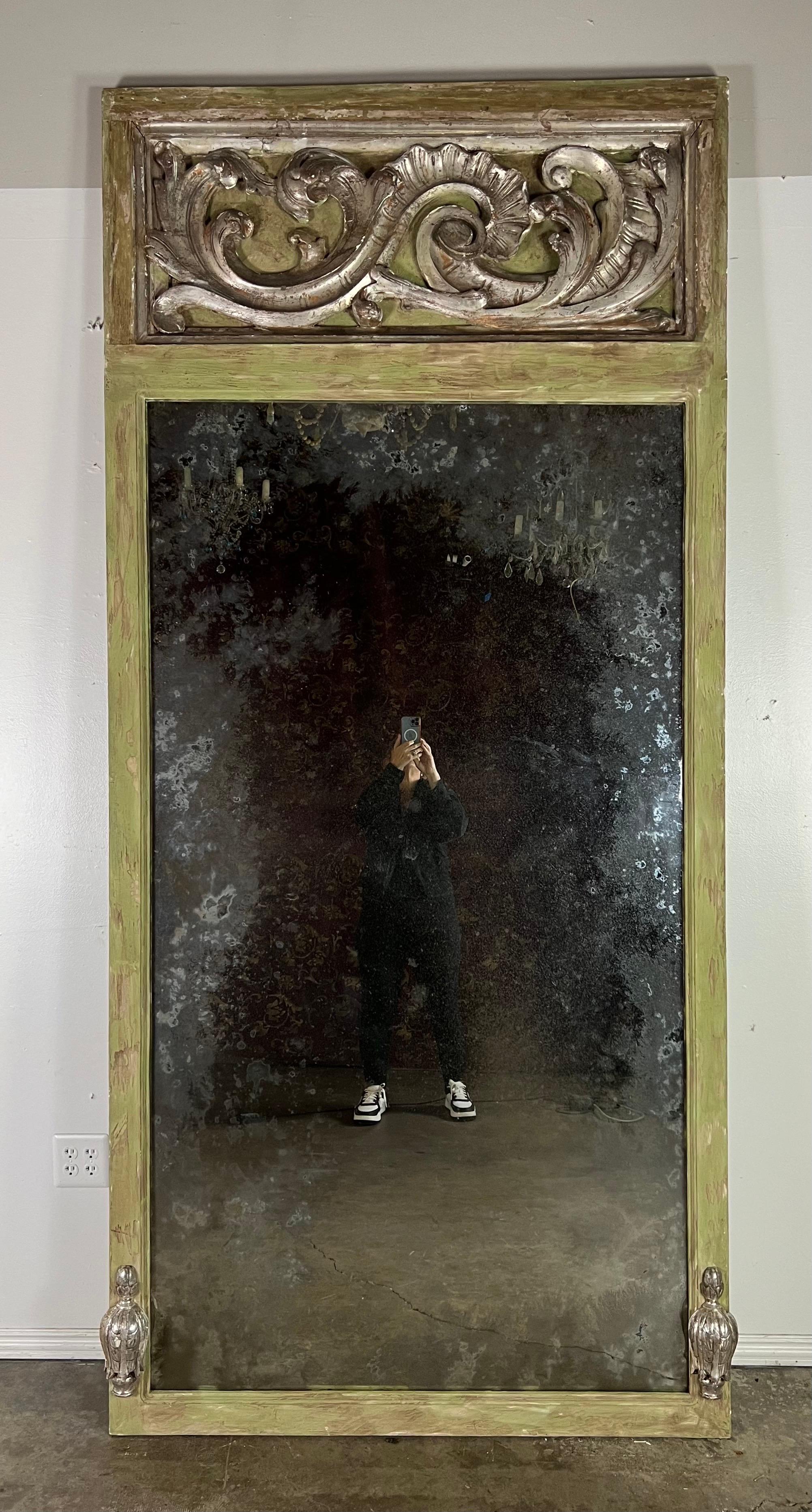 Grand miroir trumeau de style baroque italien avec un cadre peint dans une douce nuance de vert, suggérant un air de tranquillité et de raffinement qui complète magnifiquement le flair baroque de la pièce.

Un miroir trumeau comprend