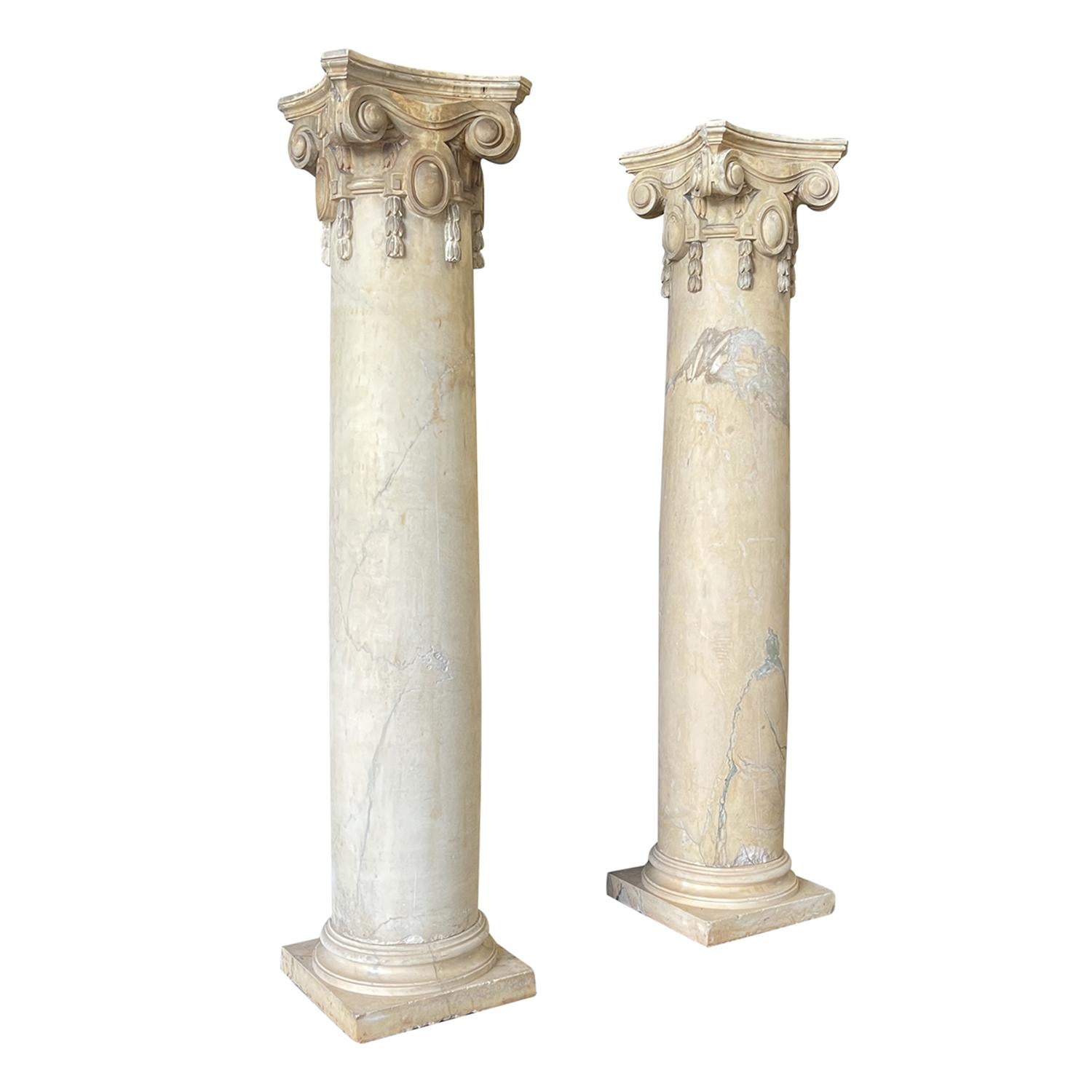 Paire de colonnes monumentales italiennes de style ionique en marbre travaillé à la main, en bon état, datant du 19e siècle. La partie supérieure des grands piliers est particularisée par des volutes, le centre des colonnes massives montre ses