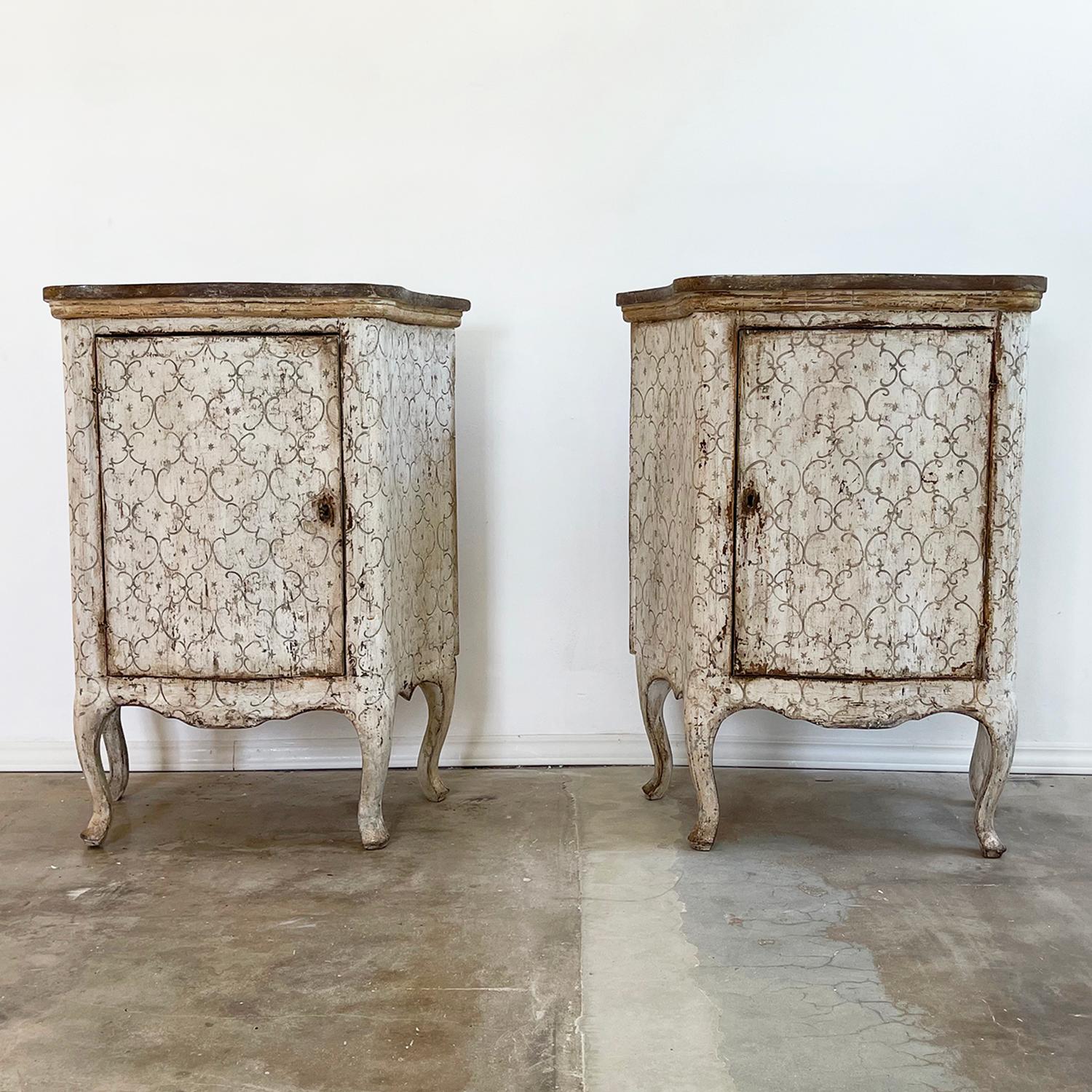 An antique Italian pair of Louis XIV small commodes in legno laccato painted light grey with a brown ornamental pattern and a door. The detailed nightstands are made of hand crafted Pinewood, consisting its original metal hardware and key, in good