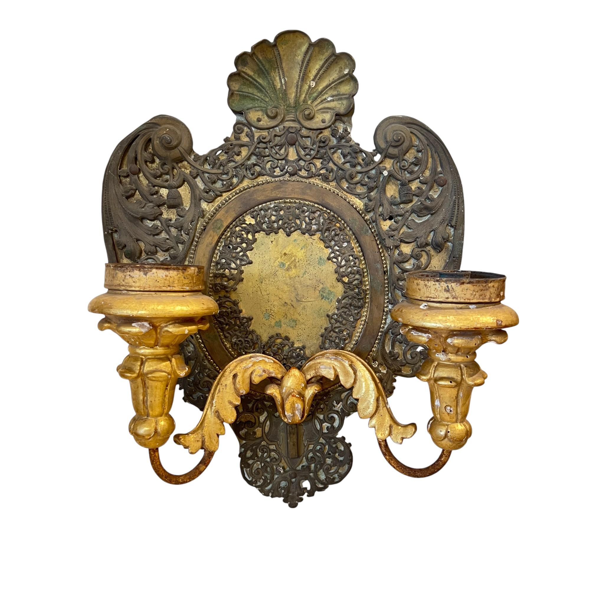 Elegant and decorative, this pair of gilded wood and tole wall sconces showcases hand-carved details and delicate tole backplate, finished in rich gold leaf for a timeless, luminous accent—perfect for adding old-world charm and sophistication to any