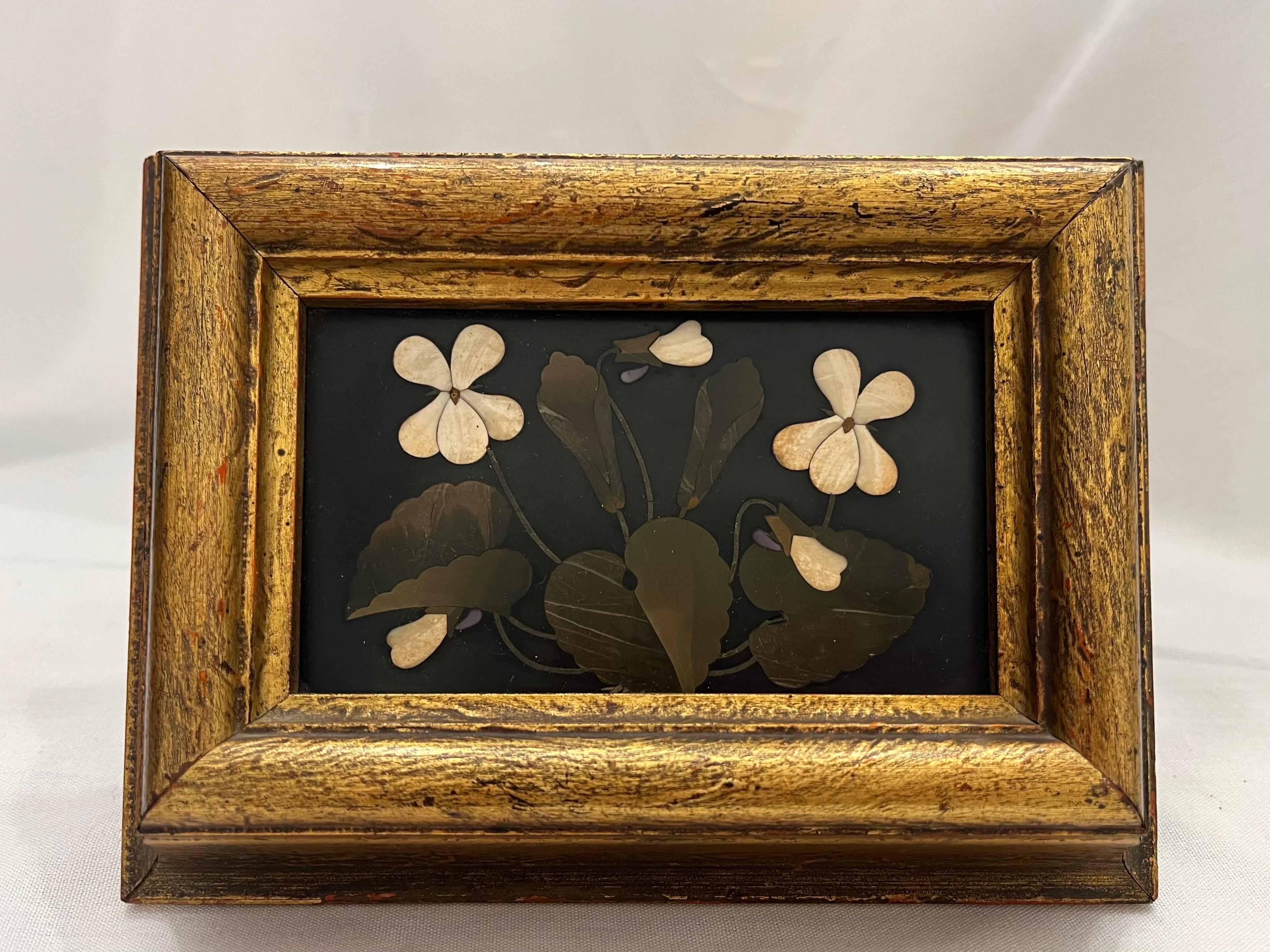 An antique, late 19th century Italian pietra dura hard stone floral still life in a frame. This incredibly beautiful pietra dura features a spray of flowers and foliage set against a deep and mysterious black background. I believe this black stone