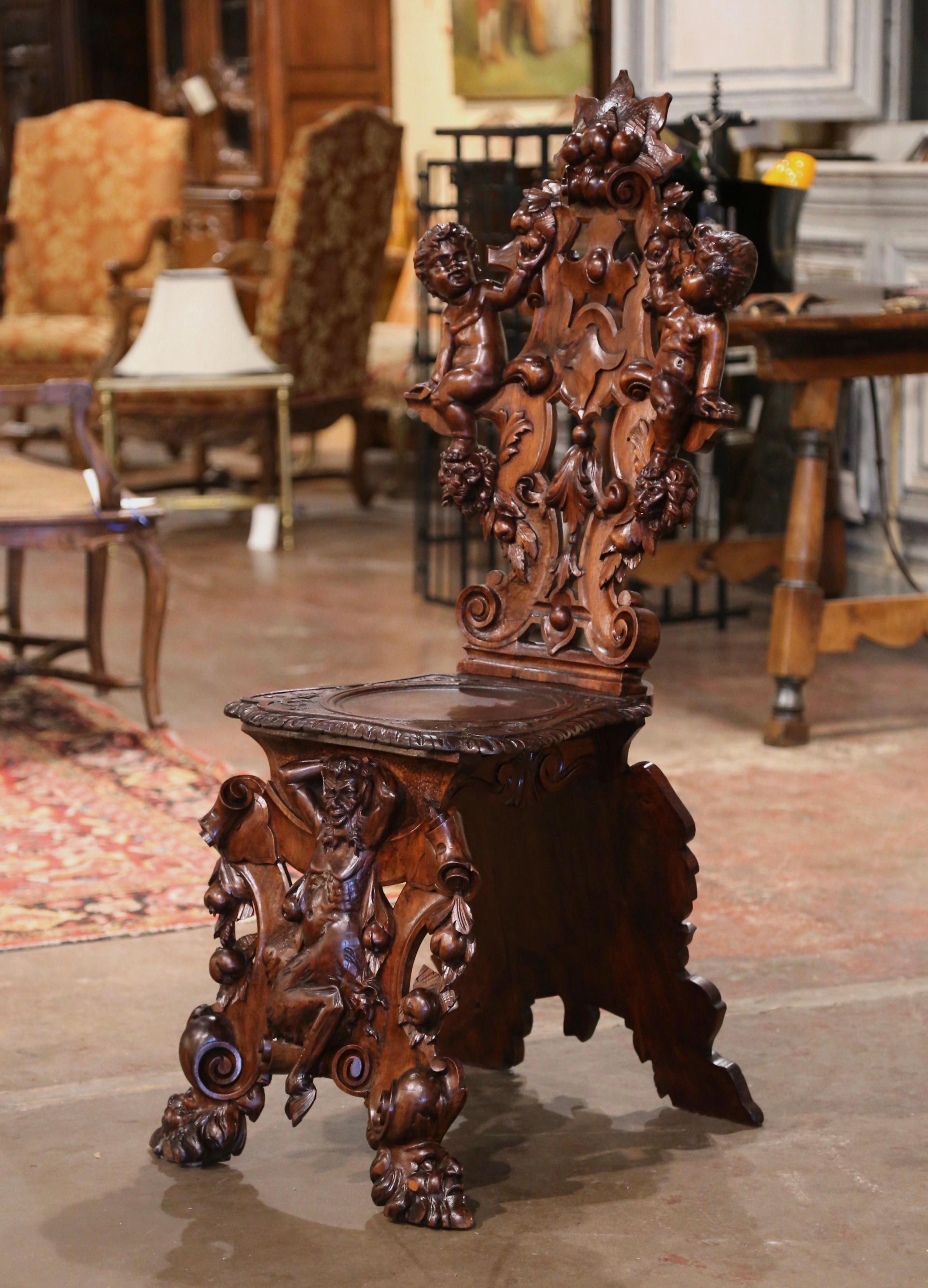Decorate a hallway with this well carved antique Sgabello chair. Crafted of walnut in Venice, Italy circa 1860, the chair stands on heavily carved and scrolled legs ending with grotesque mask faces. The center is decorated with a gargoyle figure and