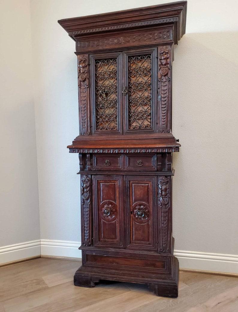 A most impressive Italian Renaissance Revival two piece court cabinet. 

Born in Italy during the second half of the 19th century, handcrafted of solid walnut, masterfully carved, later fitted with early 20th century hardware and fashioned as