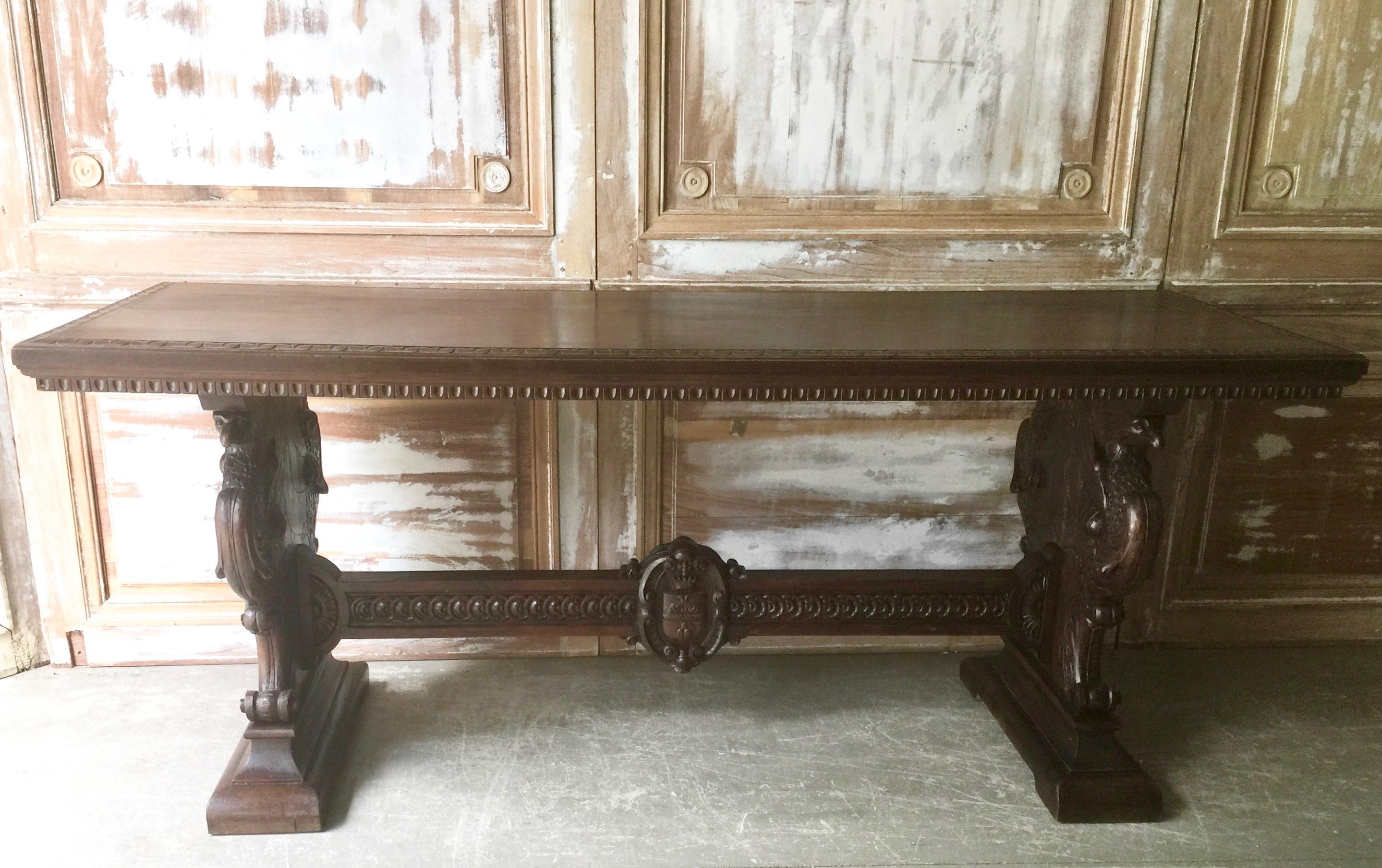 19th century extravagantly-carved Italian Renaissance-Revival library table in walnut witch carved trestle ends with griffins, female busts, northwind faces, shields, scrolls and crowns connected by a carved stretcher with the crest under the