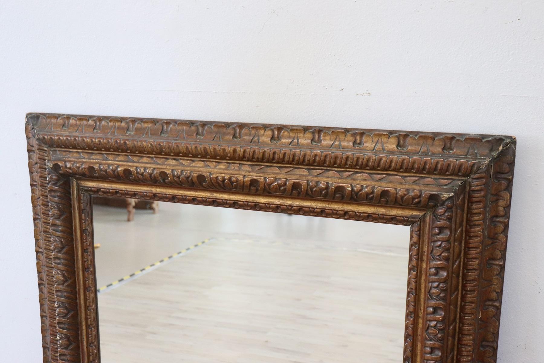 Impressive rare large wall mirror in perfect Italian Renaissance style. Made in finely carved walnut wood. High quality cabinet-making to watch wood carving with numerous curls and volutes. The color is a patinated gold similar to bronze. Mirror of