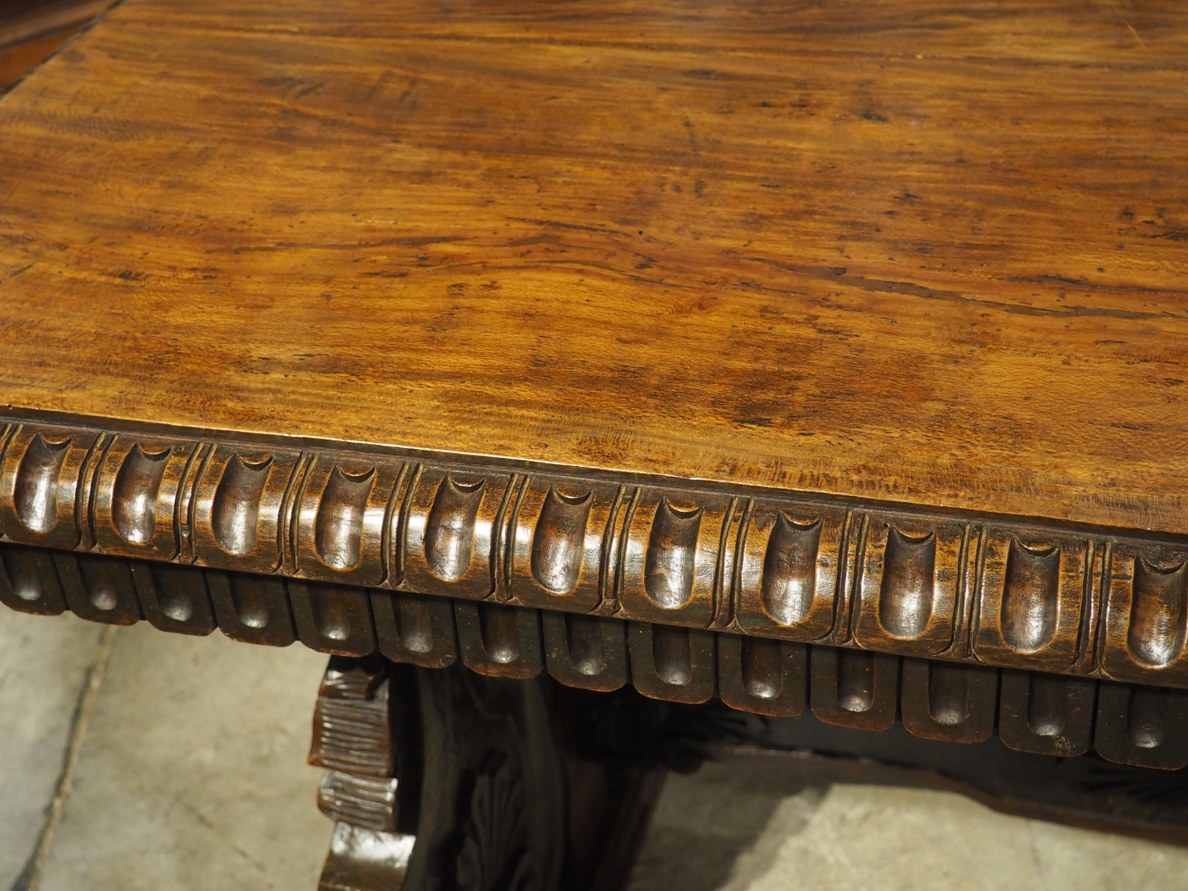 Exquisite carvings in the style of the Italian Renaissance adorn this versatile library table. Hand-carved in the 1800s, the highly detailed legs and stretcher have a deep chocolate hue which pairs well with the slightly lighter top. The