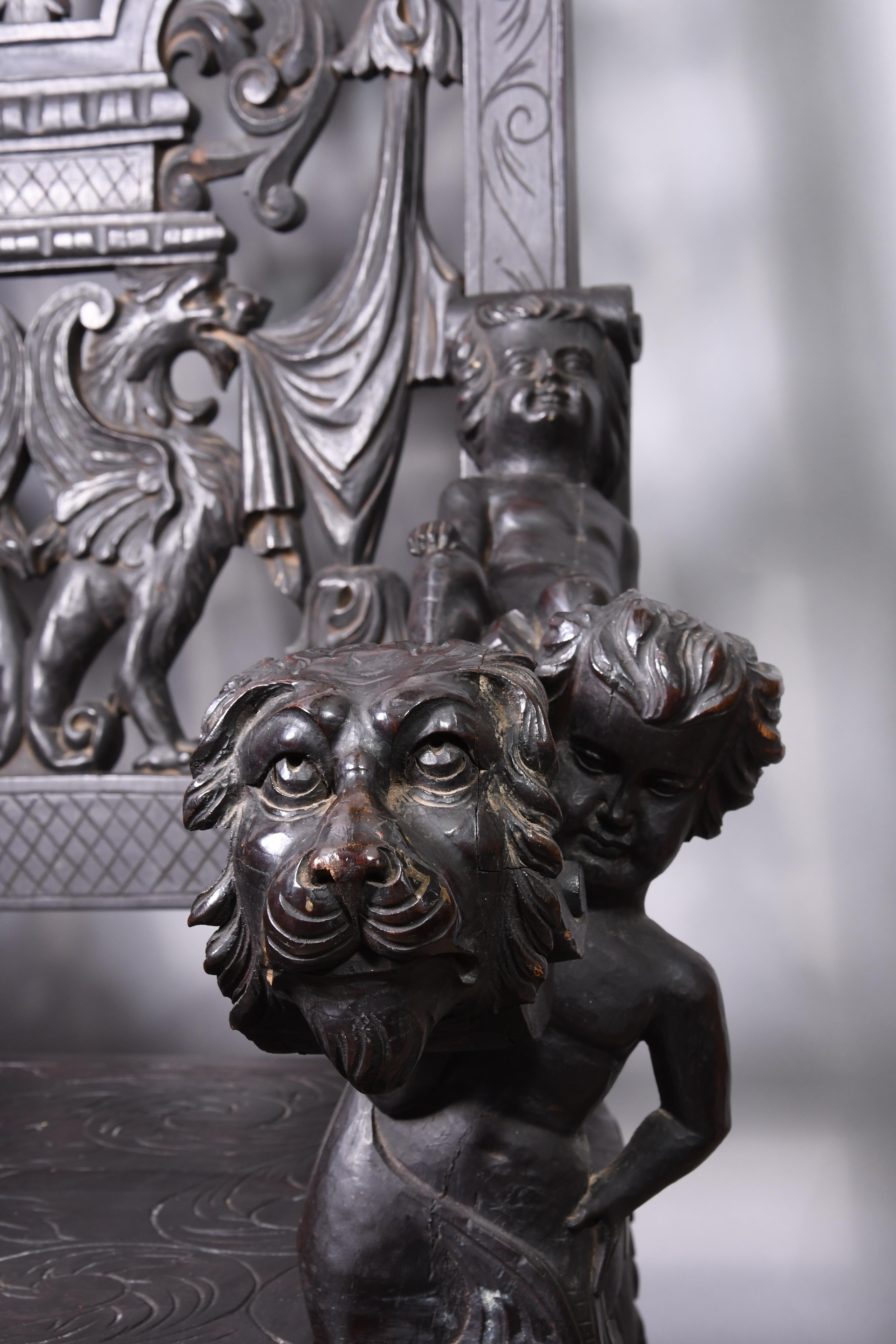 Trône entièrement sculpté avec des détails de la Renaissance tels que des chérubins, des têtes de lions, des feuillages et un dieu du vent. Les pieds sont en cabriole avec des feuilles d'acanthe, des genoux sculptés et des pieds en volute. Il est
