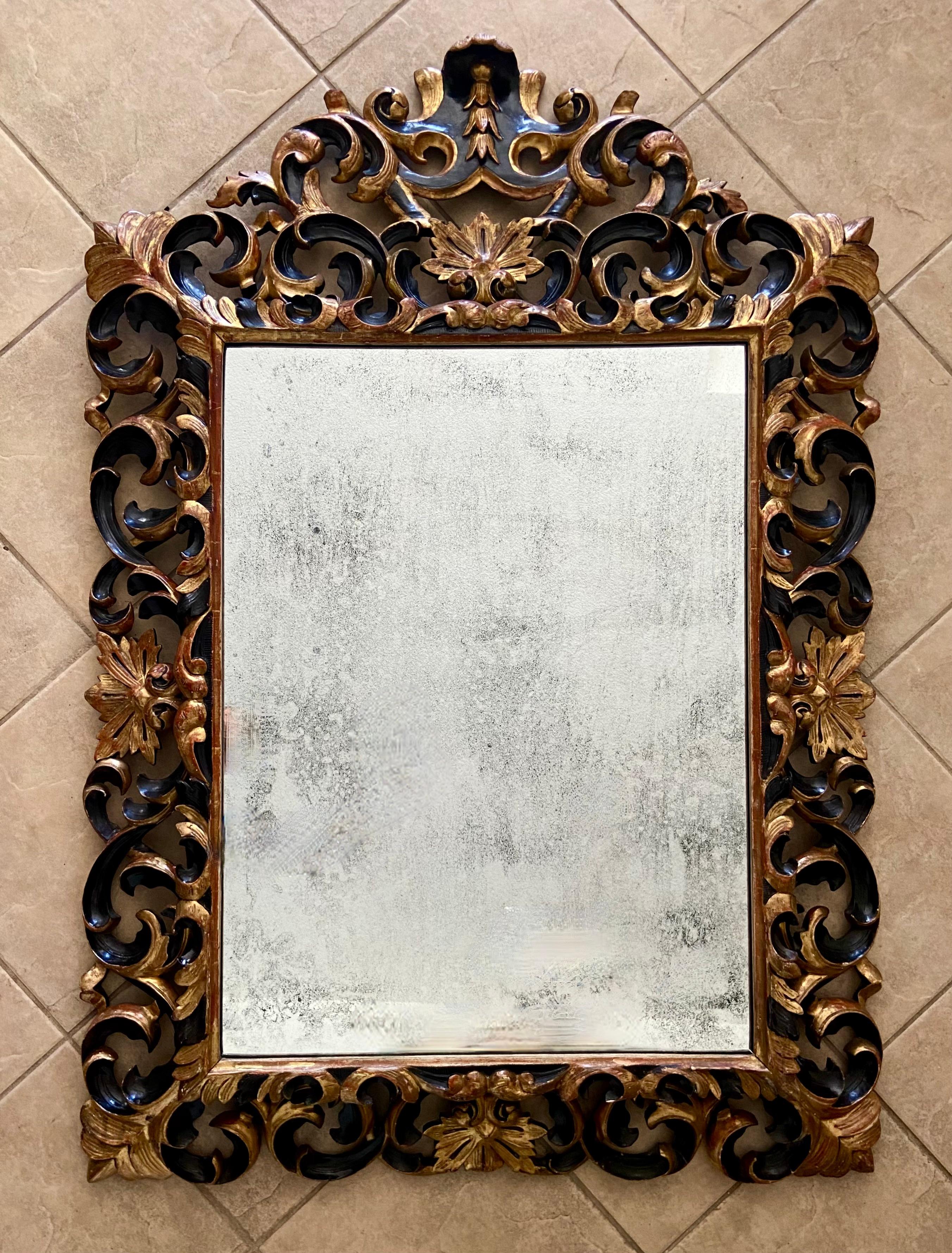 Large Italian Rococo 19th century 23K giltwood wall mirror with ornately carved filigree frame. The gold leafing has black highlights (most likely added at some later date). Large center mirror has a nice aged oxidation to silver finish. Impressive