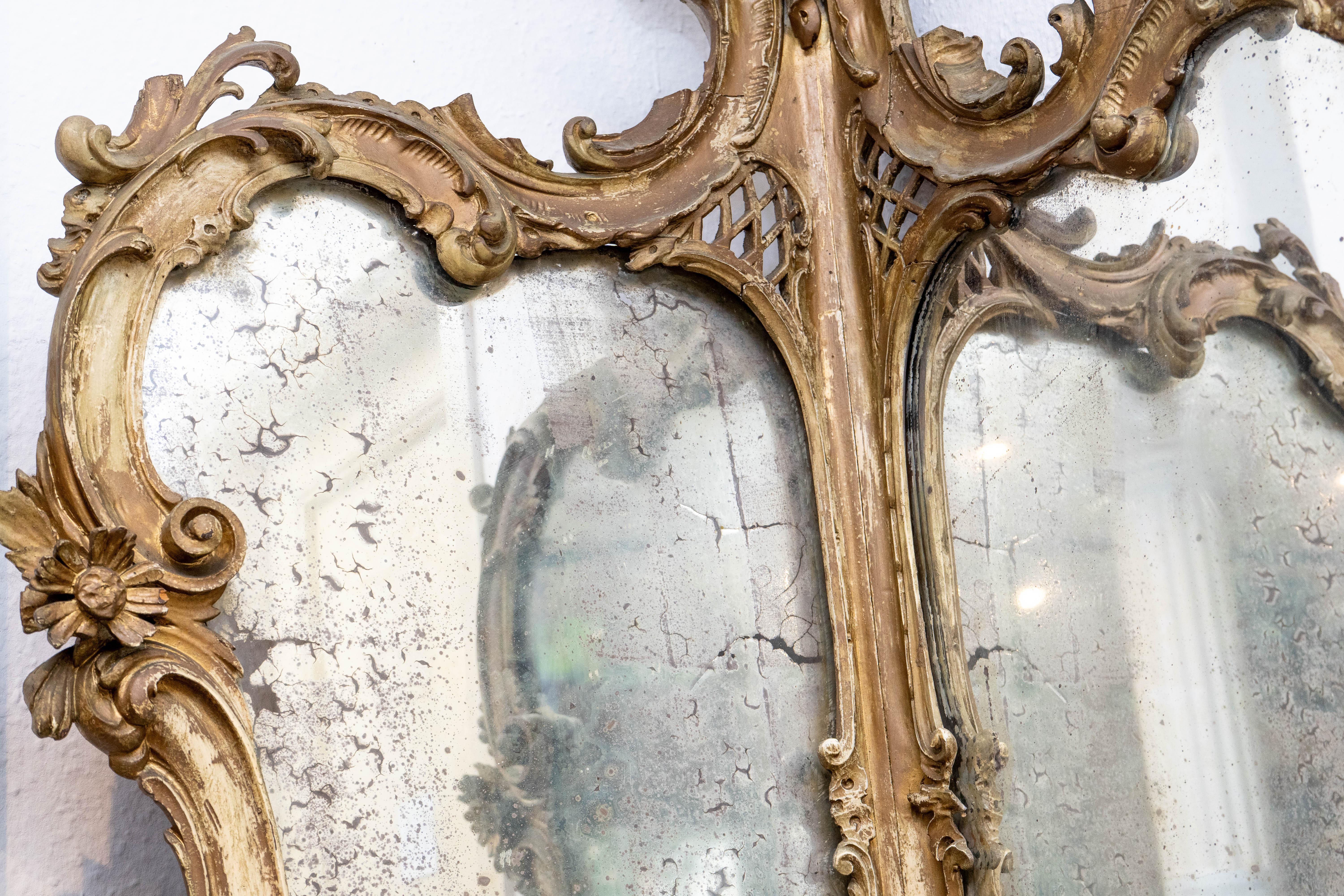 Elegant miroir d'angle en bois doré de style néo-rococo italien, datant d'environ 1820. Le cadre est richement sculpté d'acanthes et de motifs floraux. Il a conservé des traces de sa dorure d'origine qui mettent en valeur la fluidité du design