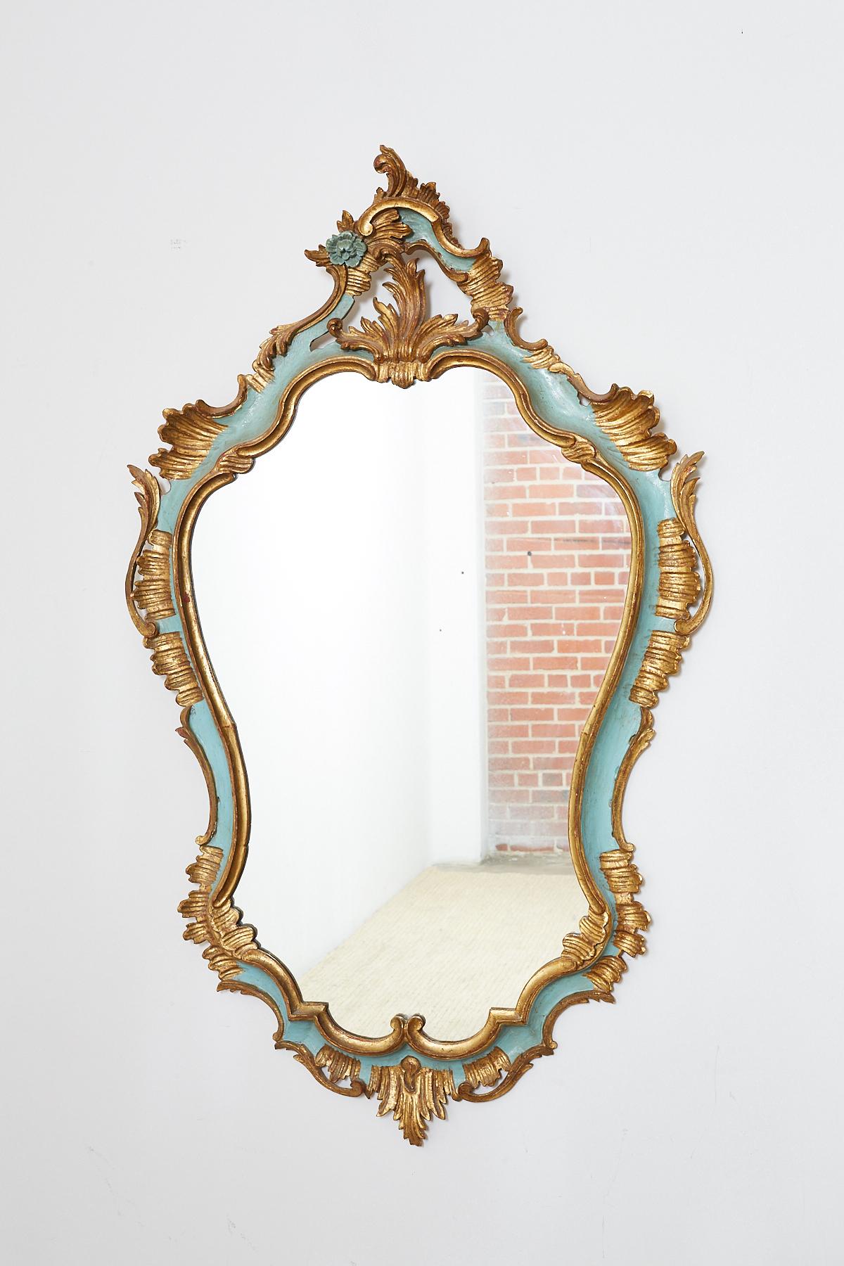 Stunning 19th century Italian carved Rococo style mirror in a cartouche form. Features a gilt finish with a robin's egg blue accent around the border. Hand-carved rocaille frame featuring acanthus sprays and flowers. Beautifully faded gold leaf