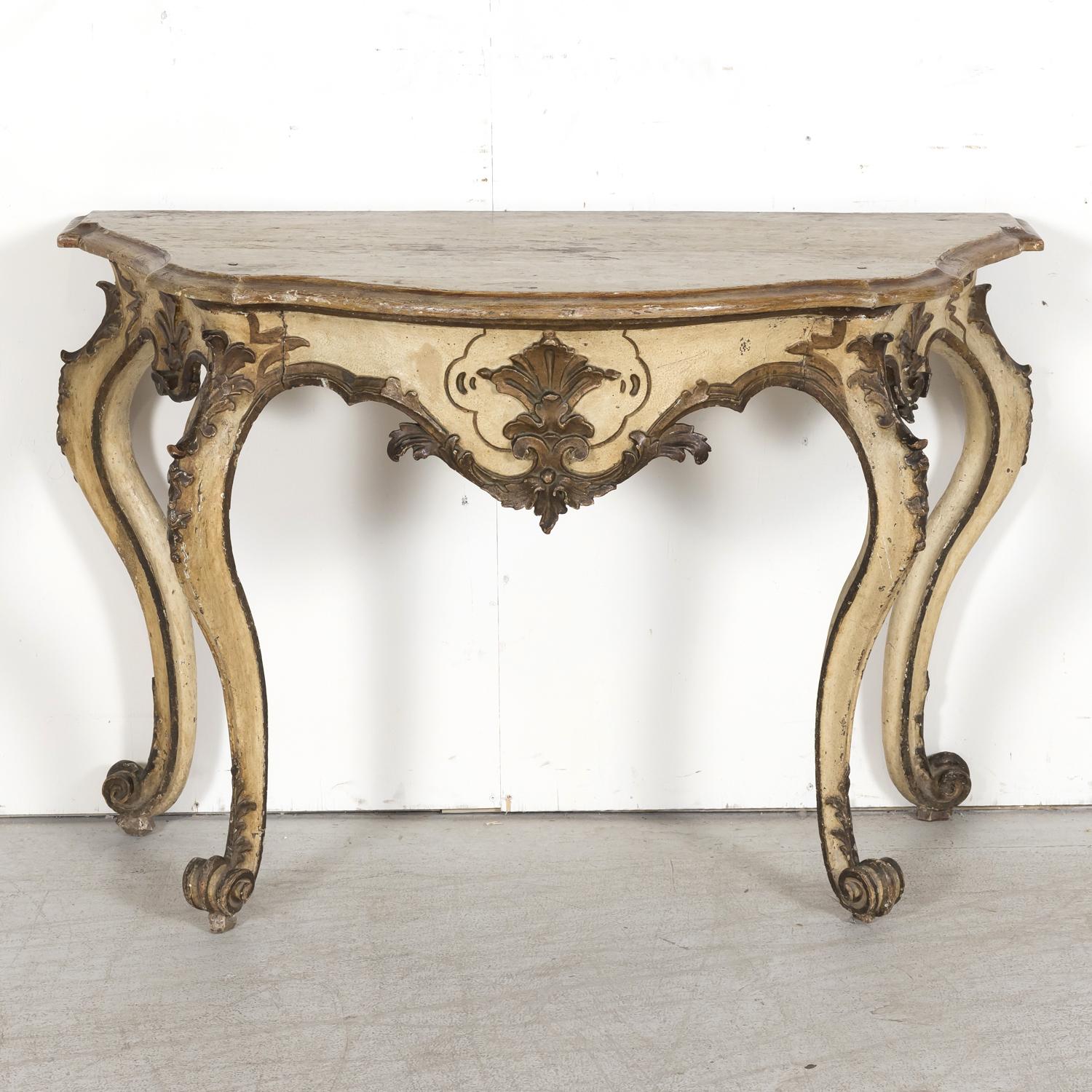 An elegant 19th century Italian Rococo style hand carved polychrome painted and parcel giltwood console table, circa 1850s. Handcrafted in Tuscany, this beautiful antique wall console features a serpentine top with beveled edge above a frieze carved
