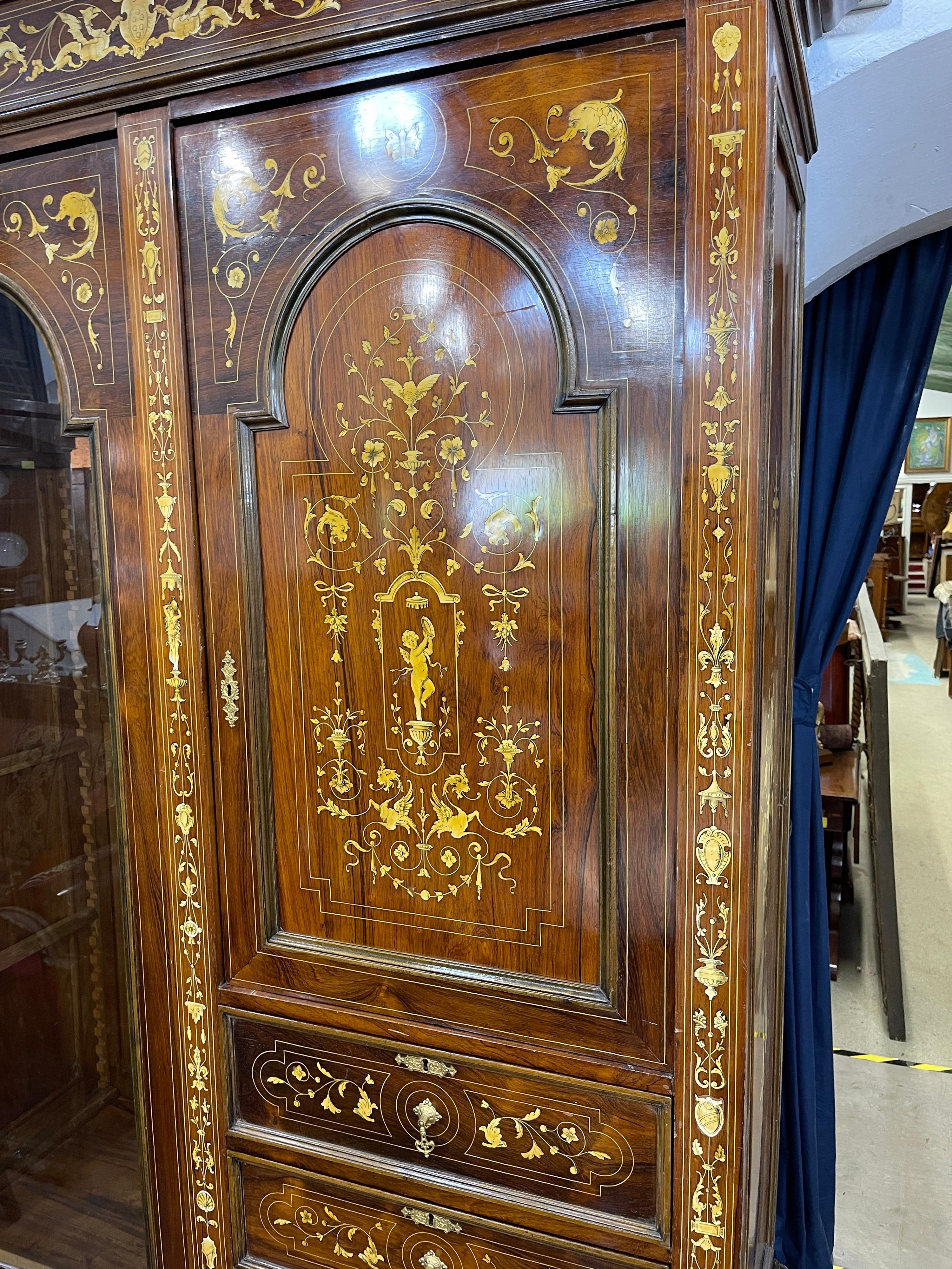 Wardrobe Vitrine cabinet veneered in rosewood and inlaid with Raphaelesque motifs in ivory.
Front with two doors, one of which is glazed, and four drawers, three of which are in columns; linear projecting top, front feet with flattened bowl. 
The