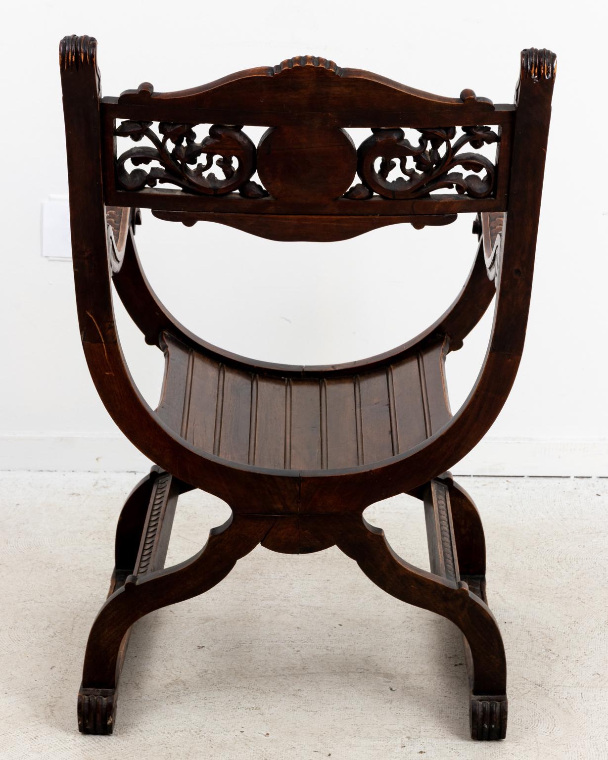 Italian Savonarola armchair in carved wood, heavily detailed with lion's face motifs on the seat back medallion and arm holds, circa 19th century. The chair also features carved acanthus leaves, scallop shell work on the top rail, and trefoil trim