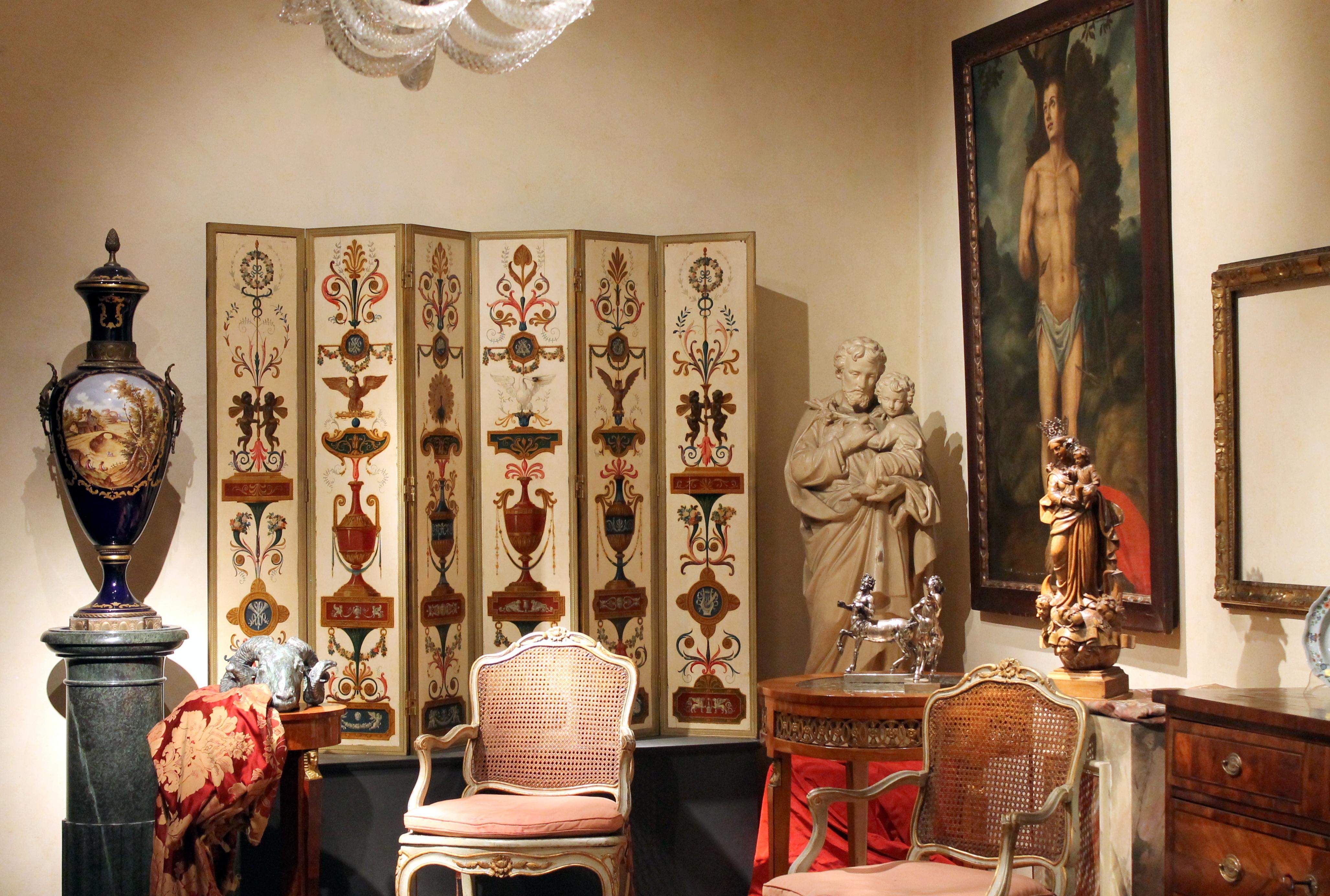 This one-of-a-kind museum quality Italian Empire Period (early 19th Century) room divider folding screen is made up of six rectangular solid wood panels, each richly painted and lacquered with a nice trompe l'oeil effect and housed in gilt bronze