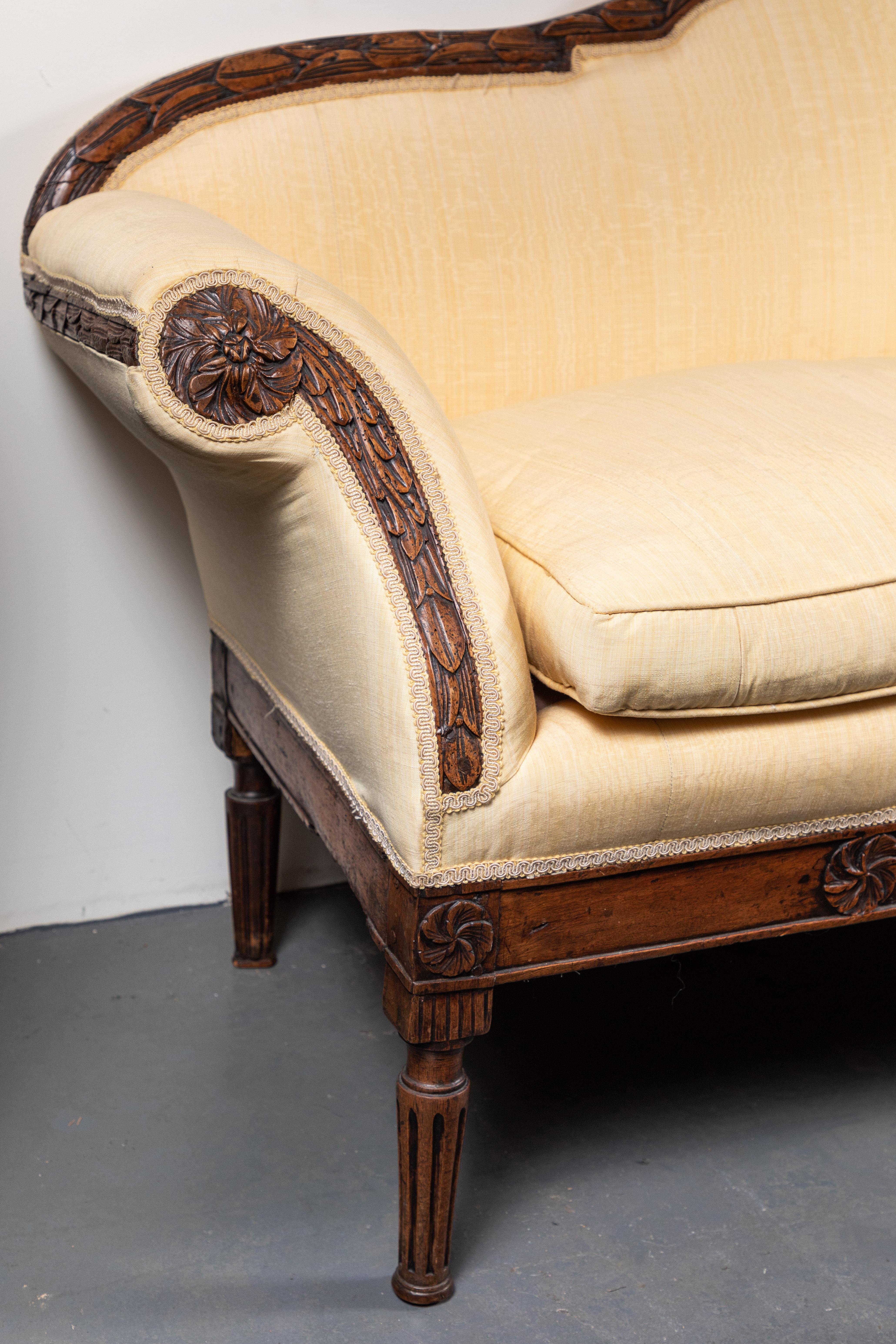 Hand carved, solid walnut, flared-arm sofa from Florence, Italy. The serpentine top rail, splayed arms, and elegant apron are filled with foliate reliefs.