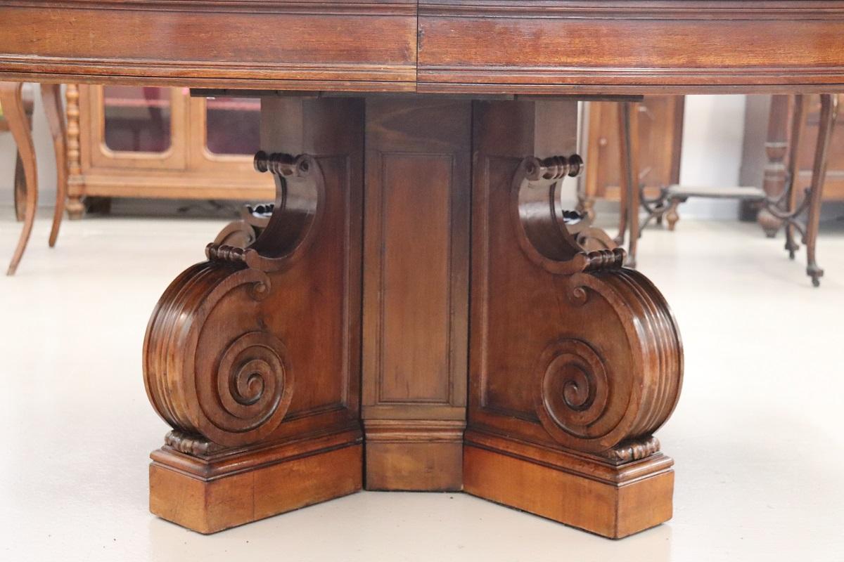 We present you a majestic antique Italian oval extendable dining table. This table is made of solid walnut wood, its oval top is supported by a large central stem with a delightful carved curl decoration. The peculiarity of this table is its