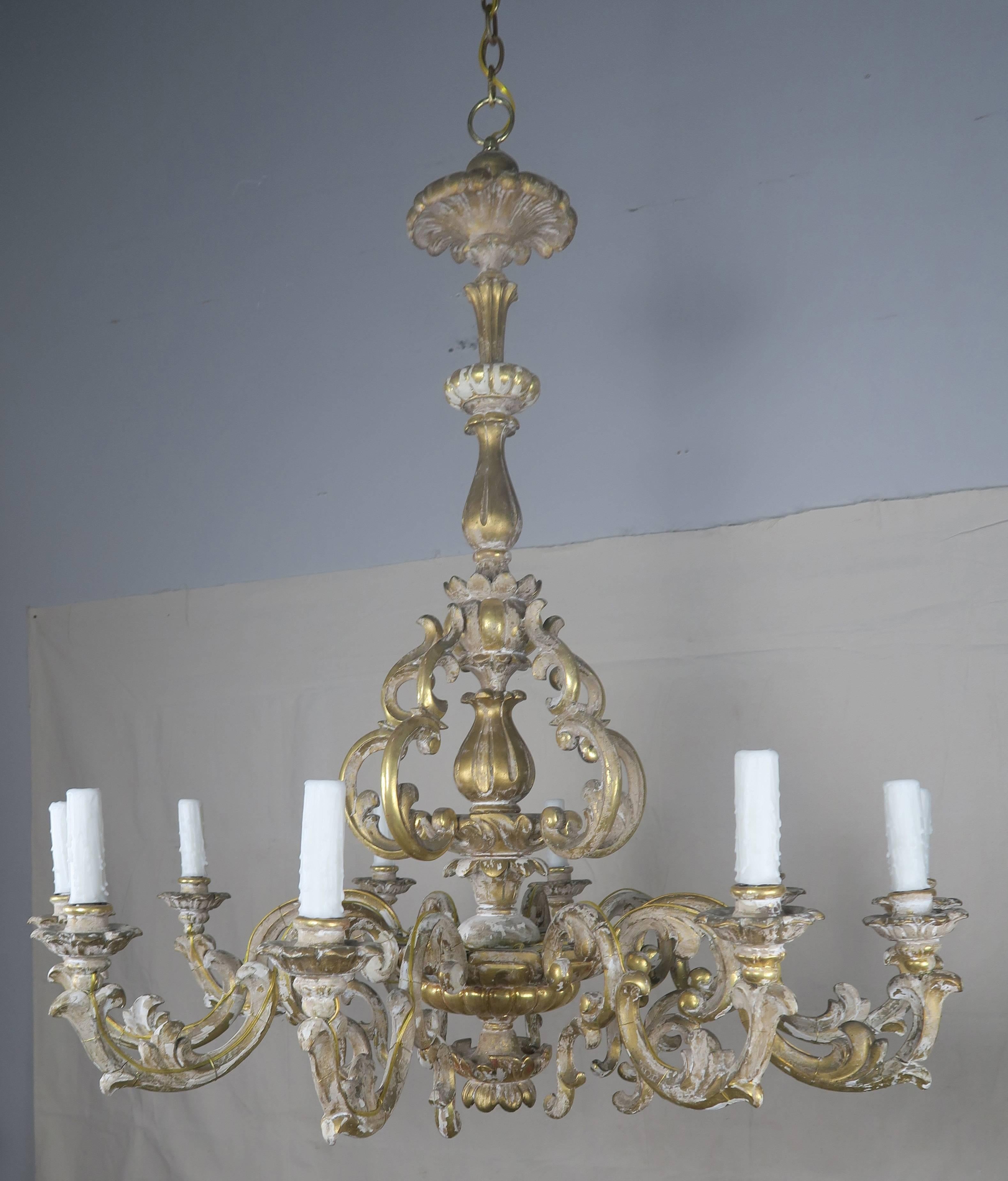 19th century Italian ten-light Rococo style giltwood chandelier that is comprised of scrolled acanthus leaves. The fixture has been wired for electricity (originally for candles only) with cream colored drip wax candle covers. Chain and canopy