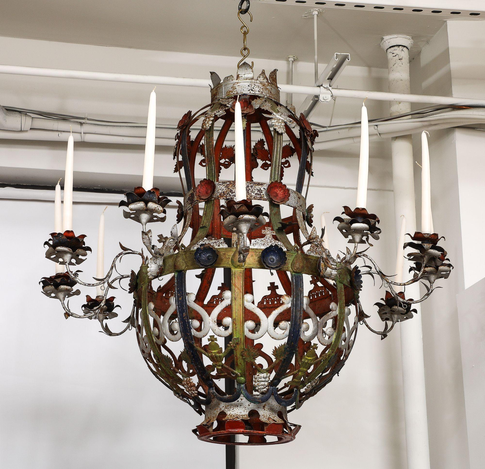 Whimsical Italian 19th Century polychrome tole 12 light chandelier, with bacchanalian theme, featuring clusters of grapes in embossed tin, the whole retaining original paint and all original foliate adorned candle arms.