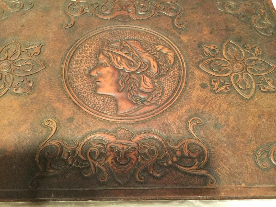 An elaborate antique Italian desk blotter in tooled leather with a center portrait along with other tooled designs and mask with scrolls in all four corners and above and below the portrait. The leather is in excellent condition with hardly any wear