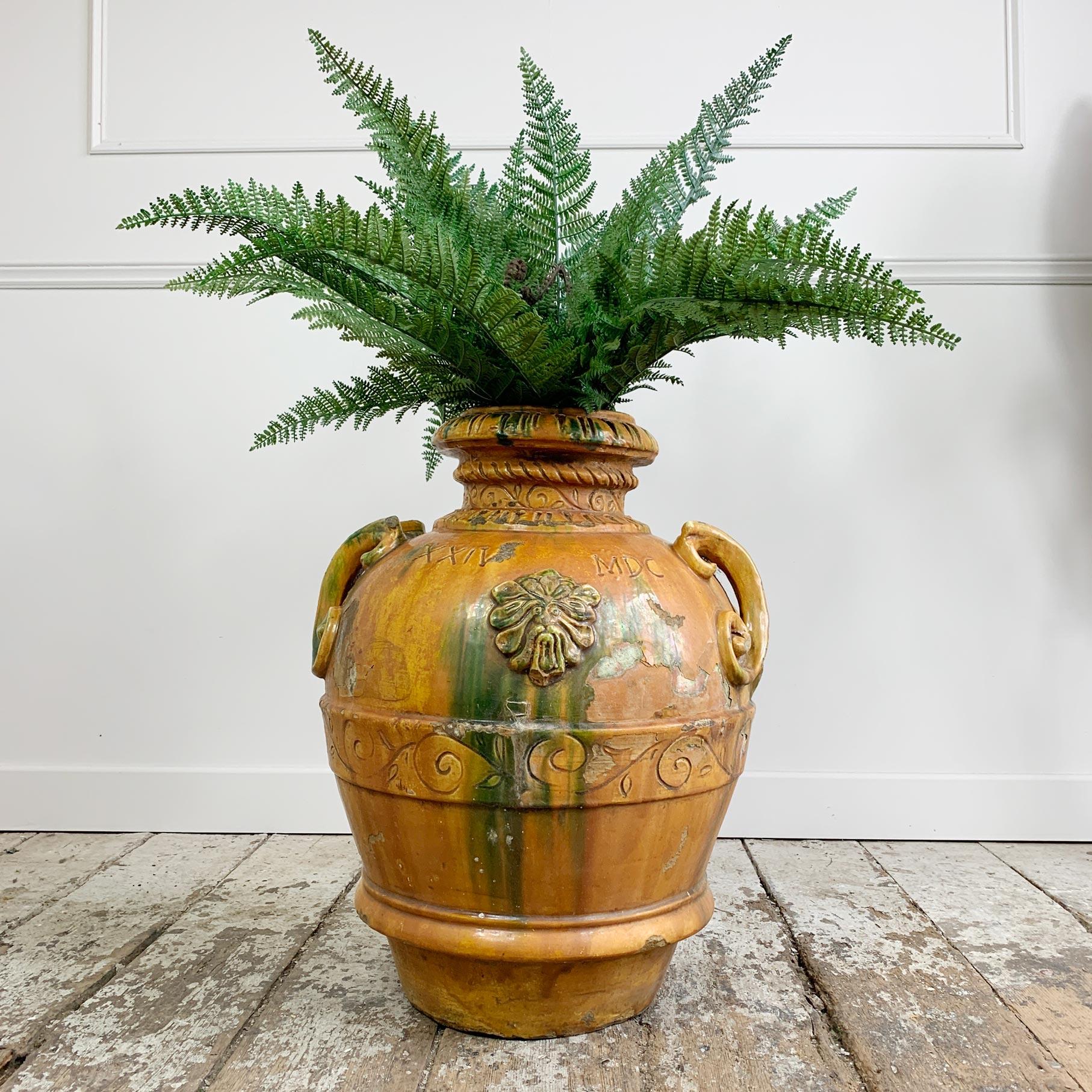 Dating to circa 1880 this exceptional Tuscan urn is decorated with incised design and has two large, scrolled handles. The applied face details to the side highlighted in green glaze over the deep orange/ochre body, the finish is almost