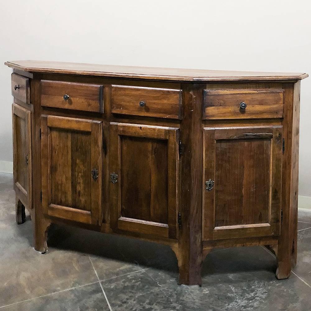 19th century Italian Tuscan rustic walnut buffet features a lighter tone and a rustic effect that is ideal for today's more casual decors. The angled sides make it very traffic friendly no matter where it's placed, and the surprising storage behind