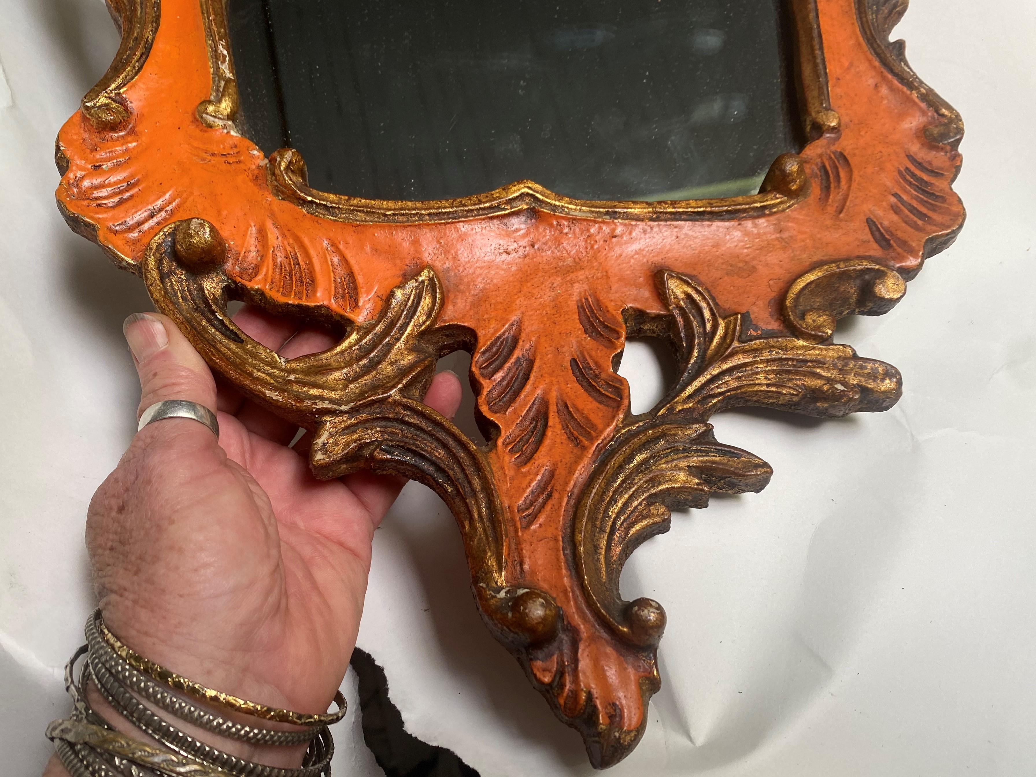 This is a lovely mirror with gold painted scroll and leaf raised and cut out carved patterns, surrounding a wonderful orange painted mirror frame which is all topped with cutout circle crest. I love that the right and left are not an exact match and
