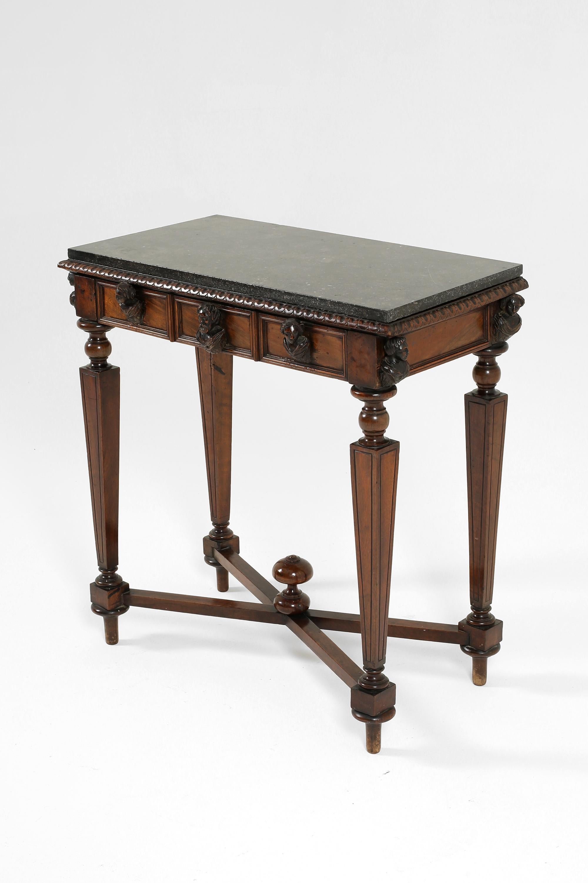 A 19th century side/lamp table in solid walnut with likely its original black marble top. Featuring carved male and female busts to the frieze, turned and carved square tapered legs and a cross stretcher with central finial. Italian, c. 1870.