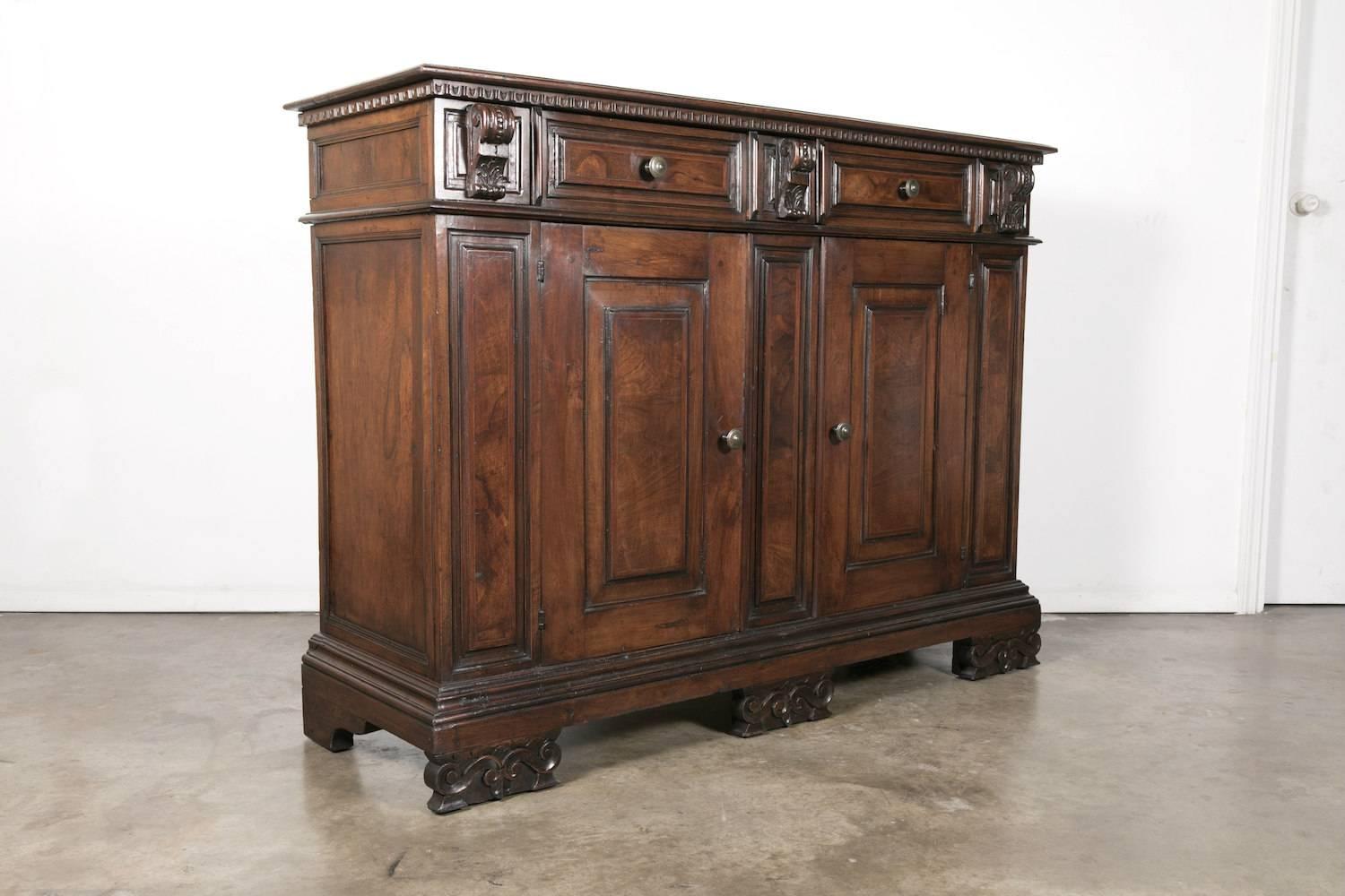 19th century Italian walnut buffet with bookmatched front and a rich patina and handsome grain pattern, from Florence, Italy. The three small acanthus corbel drawers and two large panelled drawers sit over three column panels and two panelled doors.