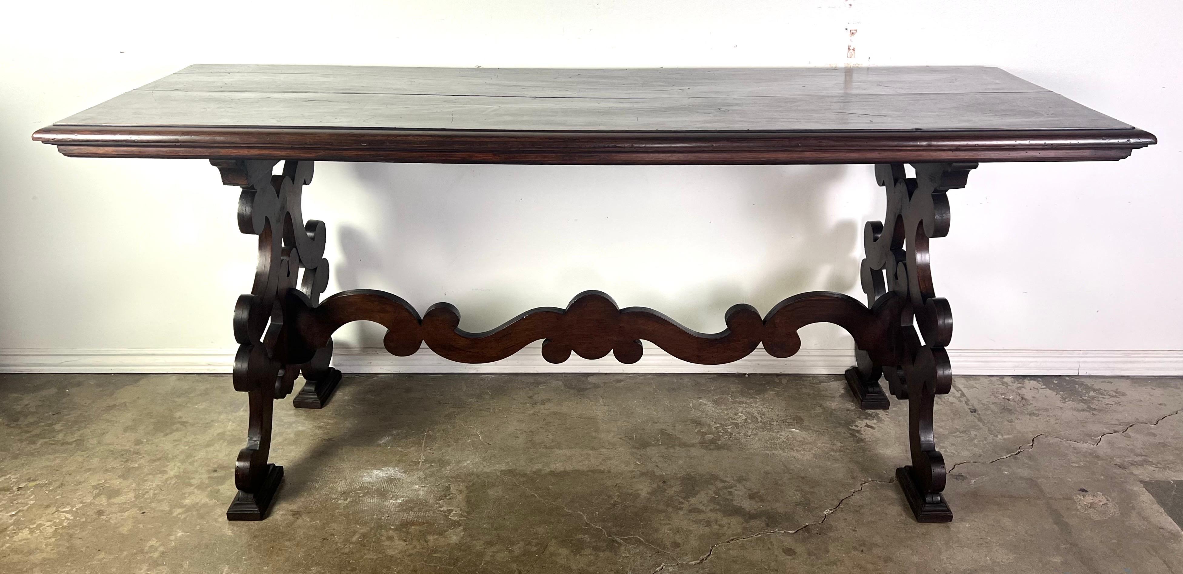 19th-century Italian Baroque style console table, standing on two pedestals made from scrolls and connected by a center stretcher in a coordinating motif, represents a dramatic and ornate piece characteristic of the Baroque period.  Crafted from