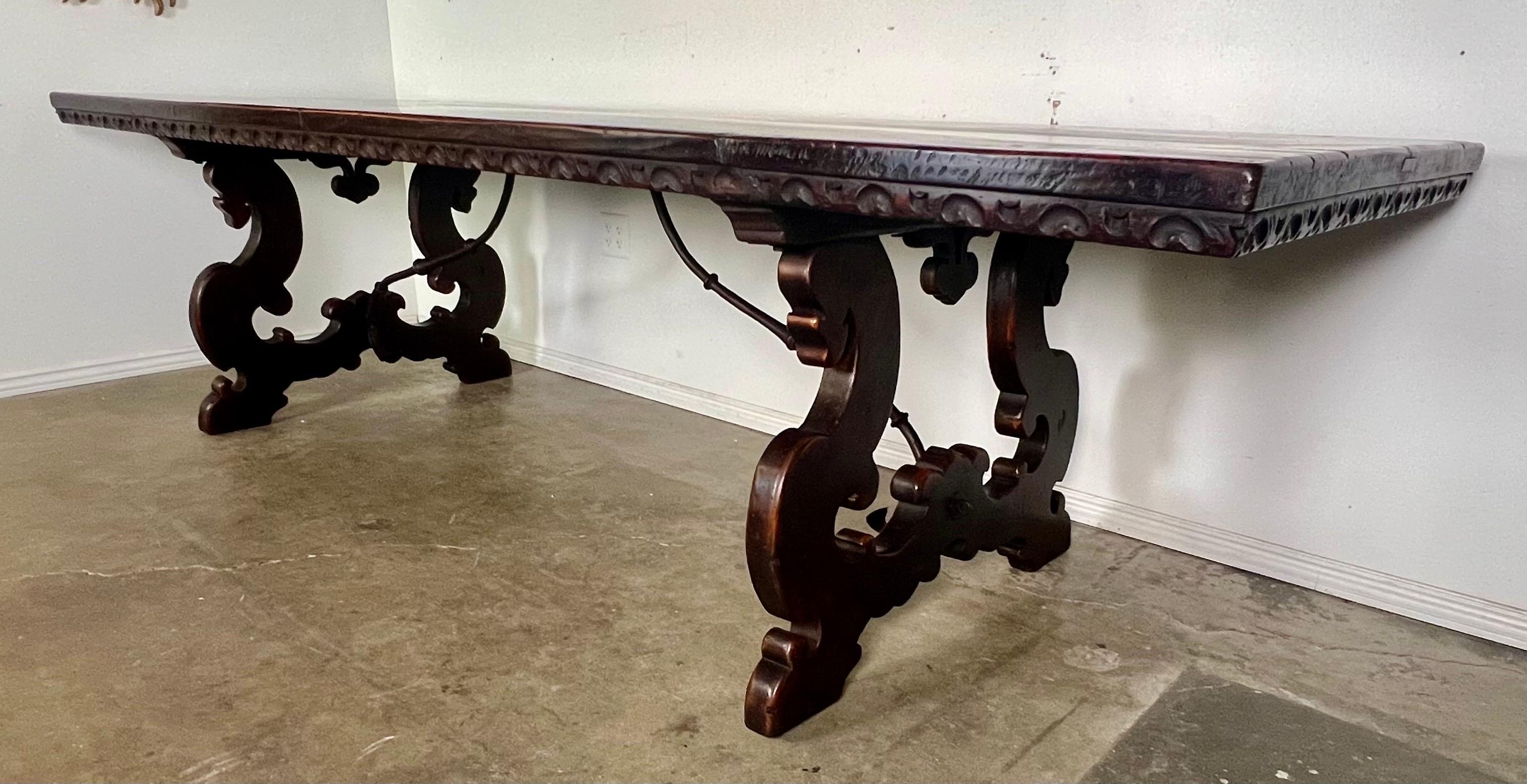 Early 19th-century Italian Baroque style dining table crafted from walnut and featuring lyre-shaped bases.  The iron stretcher adds to its durability and aesthetic appeal, while the Baroque design elements imbue the table with a sense of grandeur