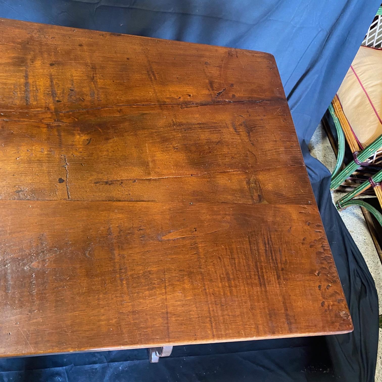 Bought in France, this lovely Italian dining table boasts hand made wrought-iron stretchers from the 19th century. This classic walnut table features a sturdy rectangular top sitting above an exquisite base made of splayed carved legs connected to
