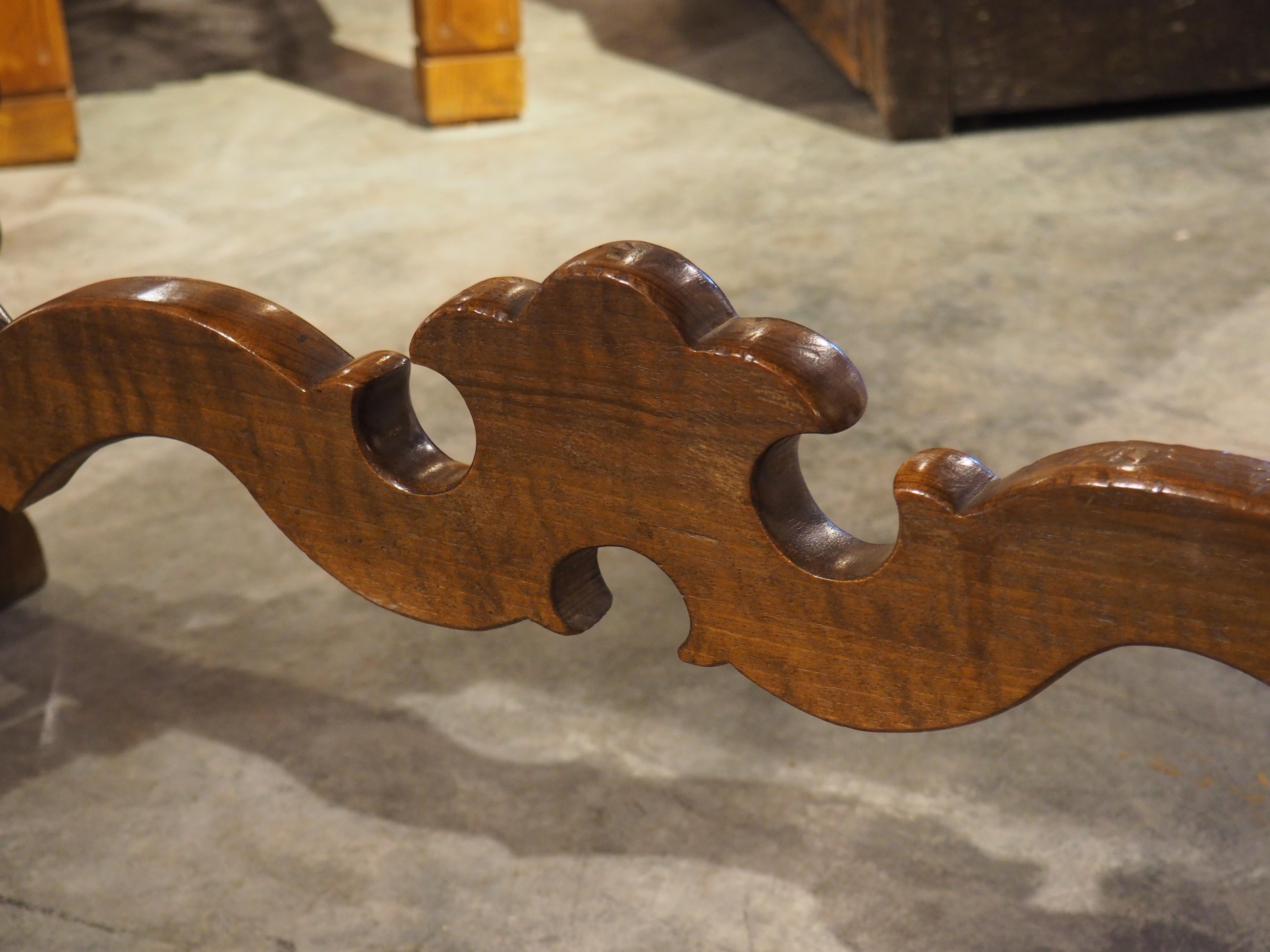 The dynamic shapes and ornate detailing associated with Baroque-style furniture are unmistakable on this Italian lyre leg table. Hand-carved in the late 1800s from walnut wood, the open lyre legs and accompanying stretchers have been embellished