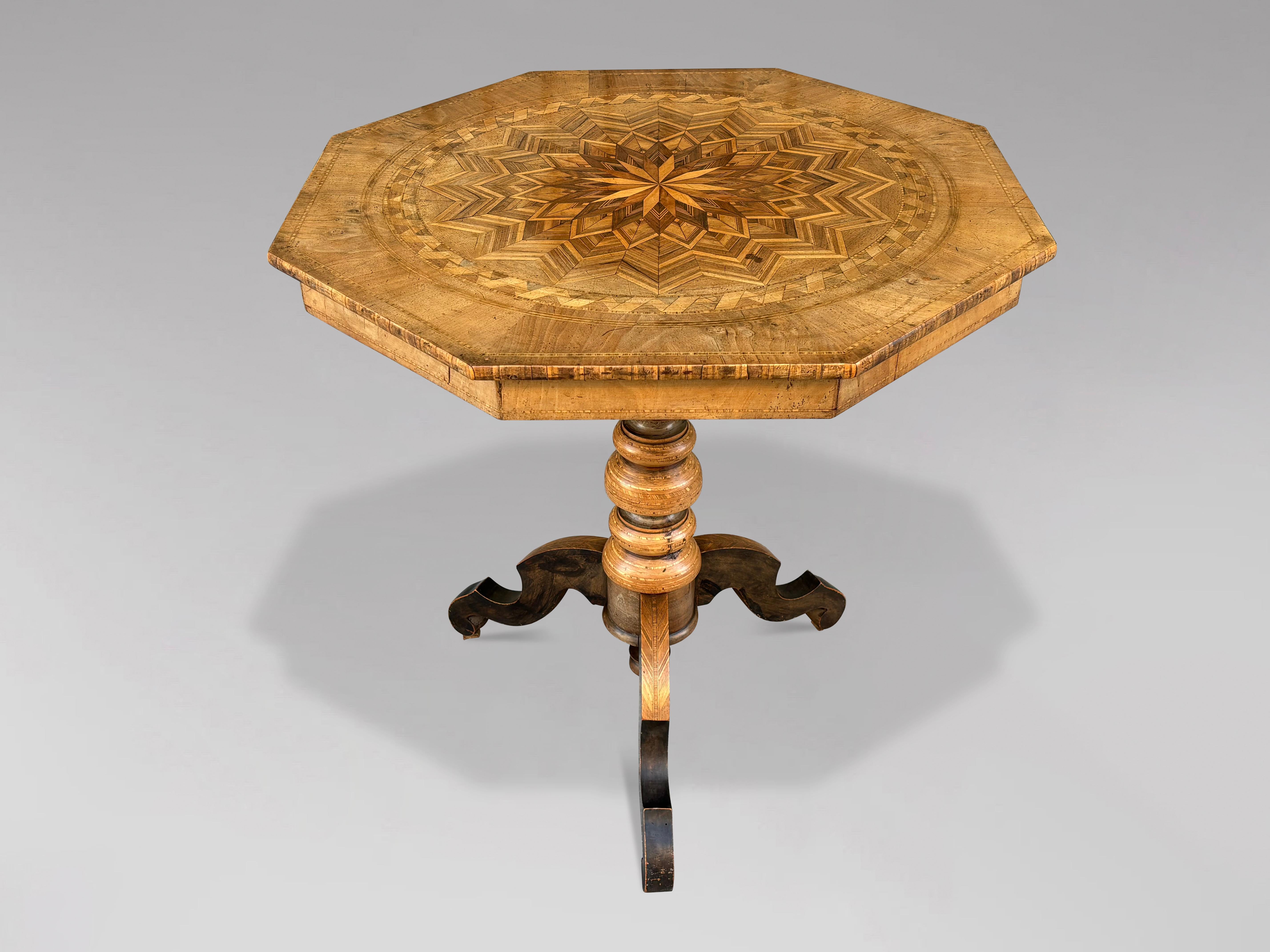 Très jolie table octogonale italienne à piédestal et trépied du XIXe siècle, provenant de la région de Sorrente, fabriquée en marqueterie de noyer et autres bois aux couleurs chaudes. Le bord de la table est orné d'incrustations et repose sur un